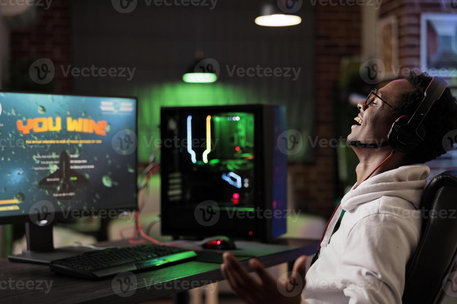 Excited gamer celebrating winning online multiplayer futuristic game match. African american man enjoying leisure time at home, feeling ecstatic about gaming championship victory photo