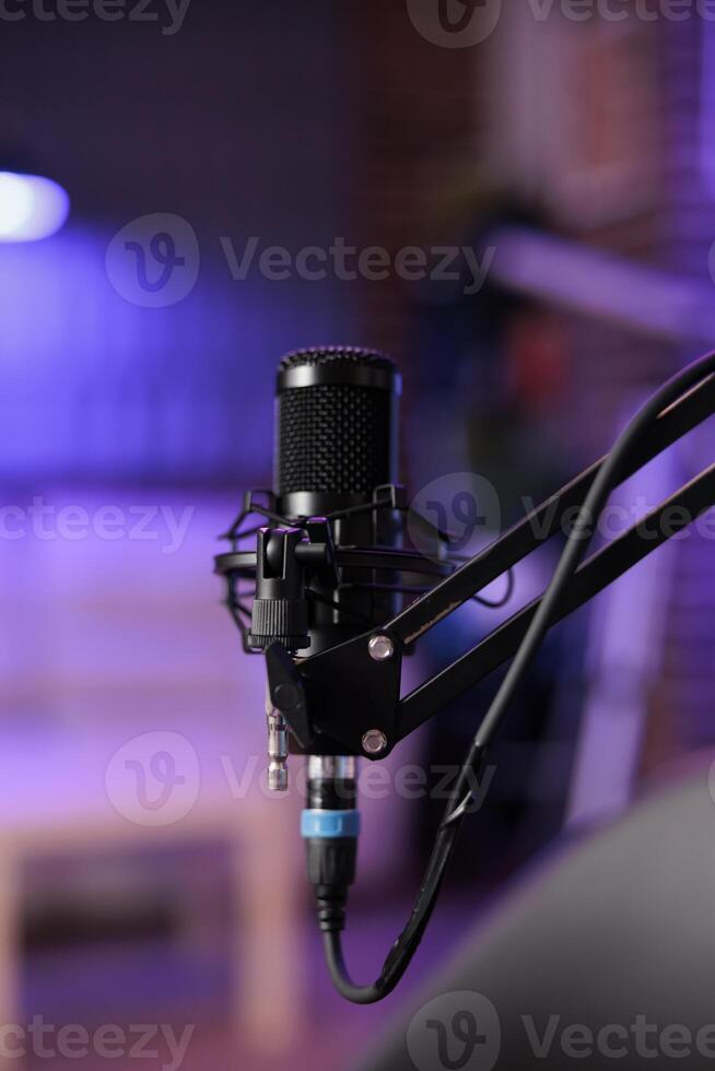 Close up shot of podcast microphone used to record conversations for internet livestreaming show. Streaming sound capturing and recording technology in empty home studio with neon lights photo