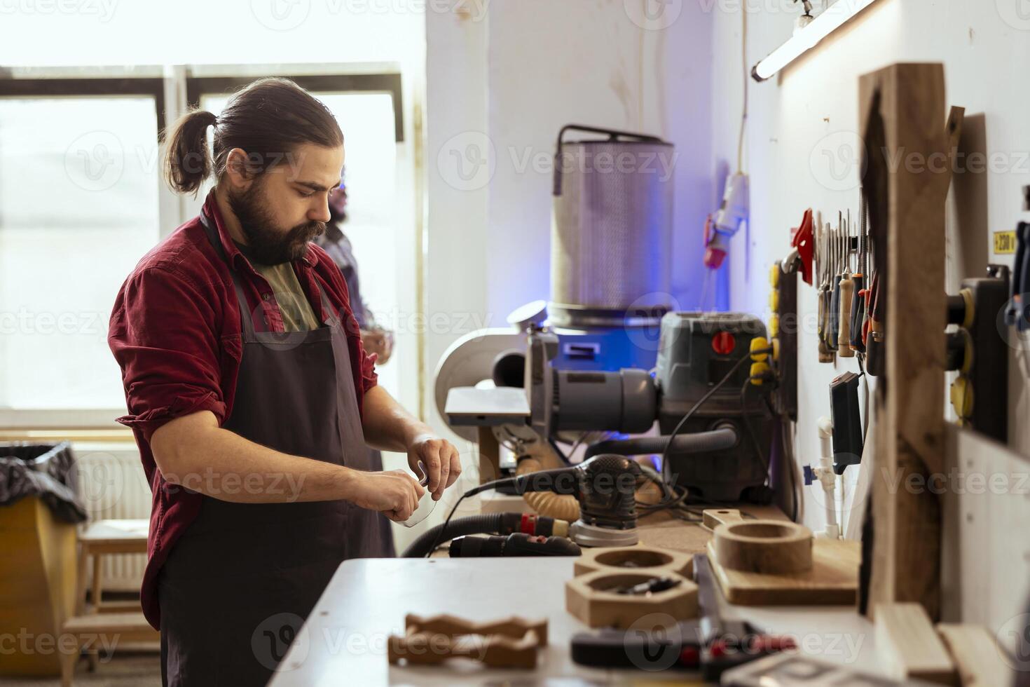 Cabinetmaker in joinery putting on protection glasses before assembling furniture. Woodworking professional preparing safety gear in carpentry studio before starting work photo