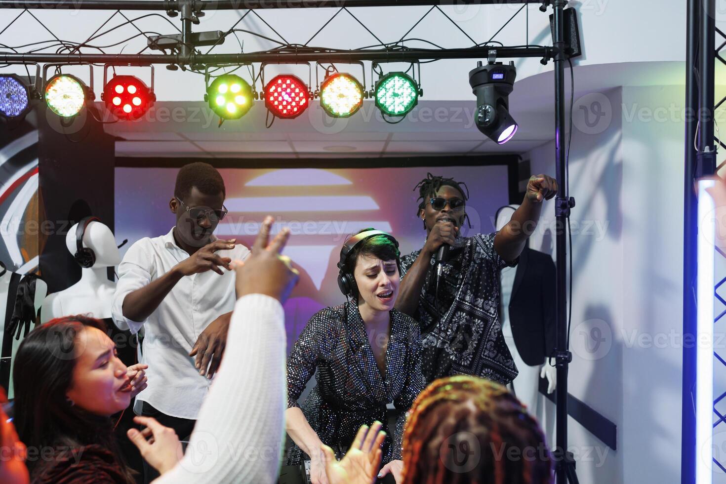 Group of diverse musicians playing on stage and engaging clubbers crowd to party in nightclub. Music band performing while young people dancing and cheering on dancefloor in club photo