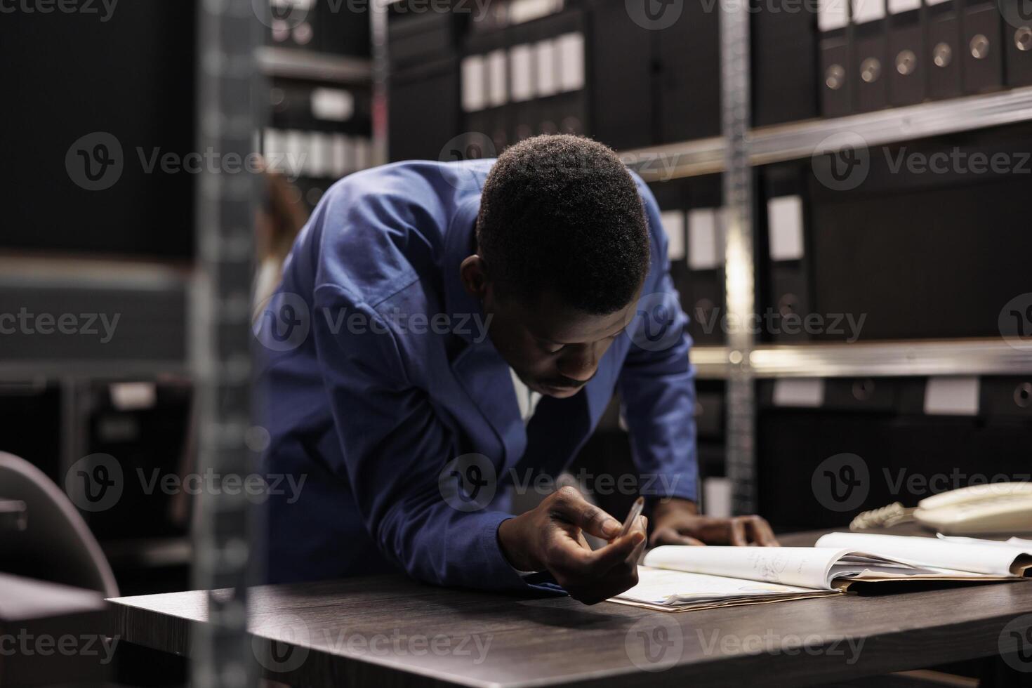 African american manager brainstorming ideas while working at accountancy research, analyzing bookkeeping report. Businessman searching for administrative record working overtime in arhive room. photo