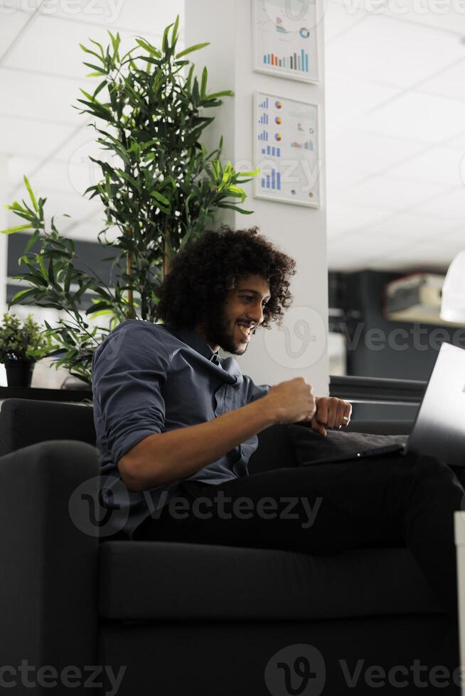 Happy executive manager celebrating successful product sales while working in start up business office. Excited company employee rejoicing investment profit in coworking space photo