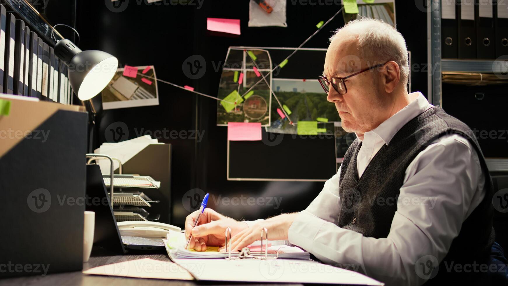 Investigator reading statements to connect the dots in solving crime, using confidential forensic reports. Senior officer working on criminal case with incriminating proof, secret mission. photo