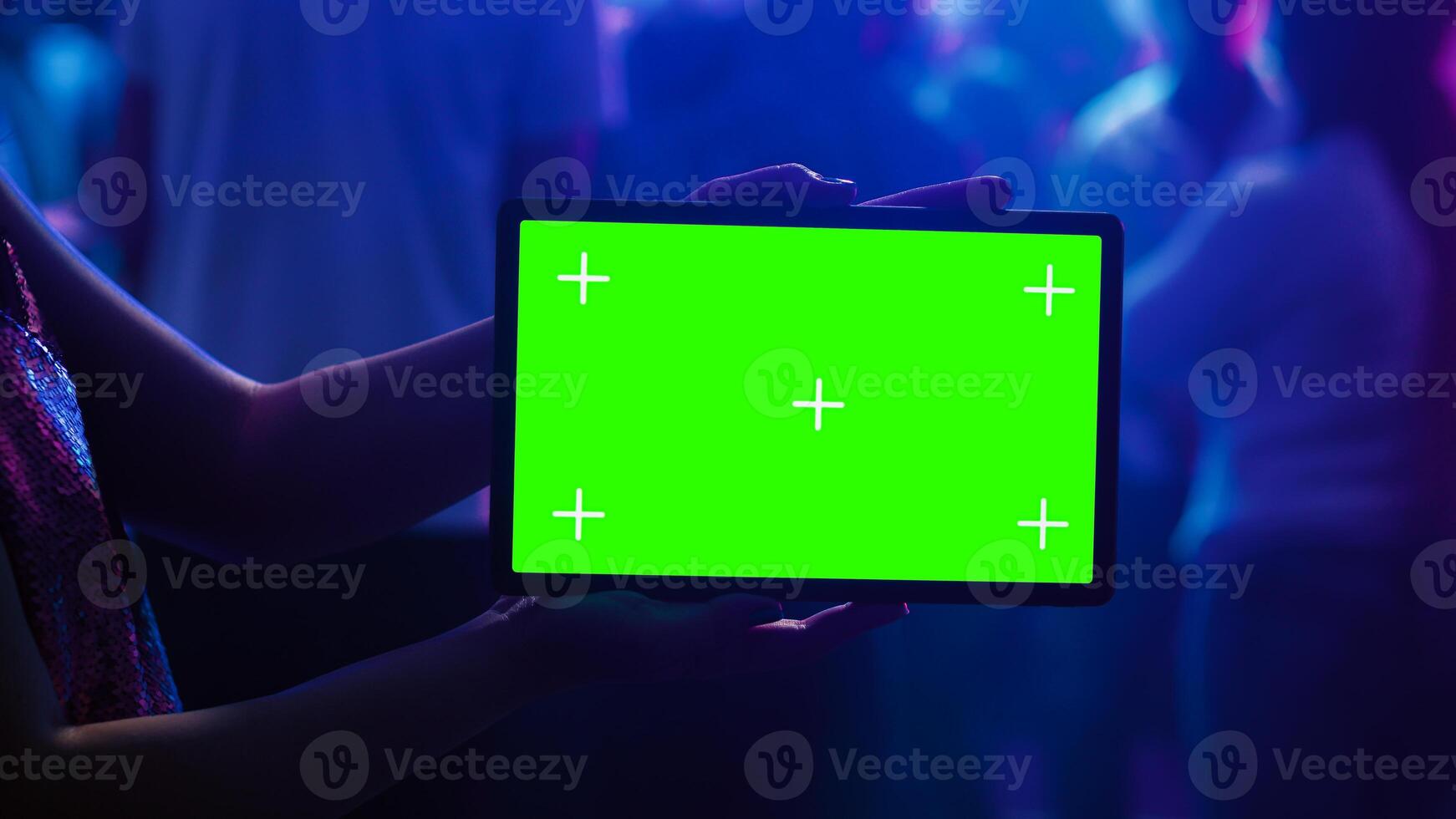 Adult using tablet with green screen at club, holding gadget with blank mockup template on dance floor. Young woman showing isolated display with chroma key and copyspace at nightclub. photo