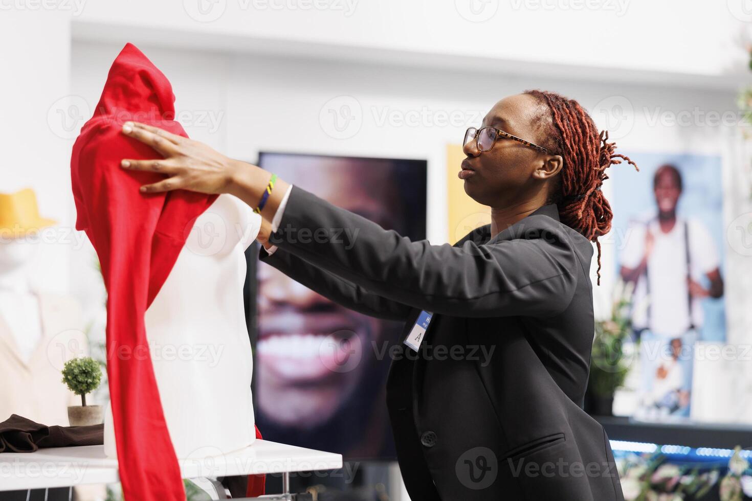 Clothes shopping mall assistant putting casual pullover on mannequin, showcasing merchandise. Fashion boutique worker dressing dummy model in blouse from new apparel collection photo