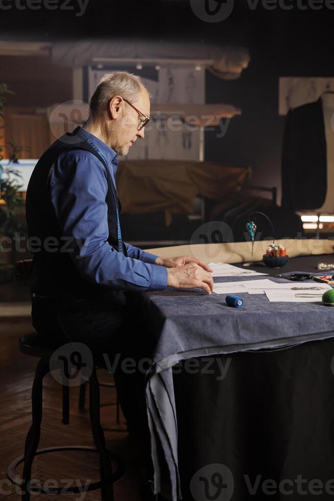 Fashion designer working on upcoming sartorial project for runway show, conceptualizing different garment combinations in atelier workspace. Creative couturier working in professional tailoring studio photo