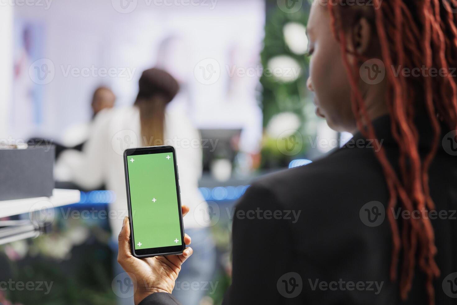 African american woman using smartphone with green screen while shopping for clothes in mall. Boutique buyer holding mobile phone with empty chroma key display for copy space photo