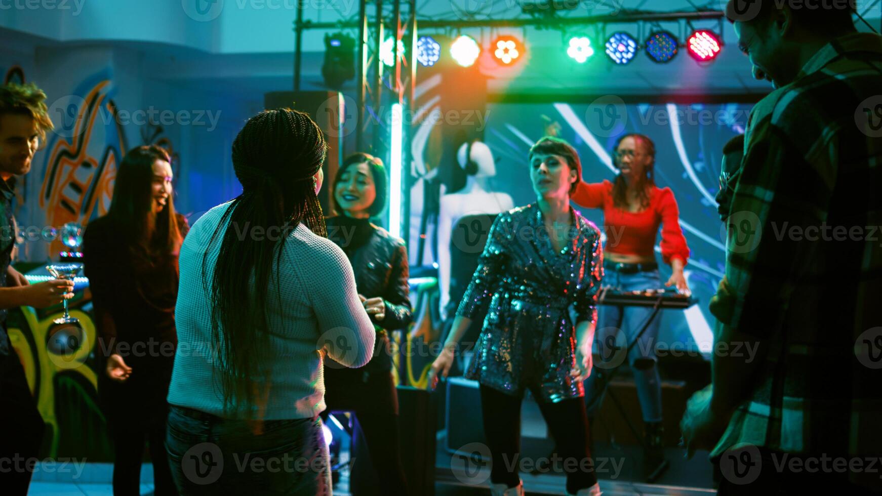 Persons having fun at dance party, partying together on electronic music at discotheque. Cheerful group of friends enjoying night out at club, dancing around for entertainment. Handheld shot. photo