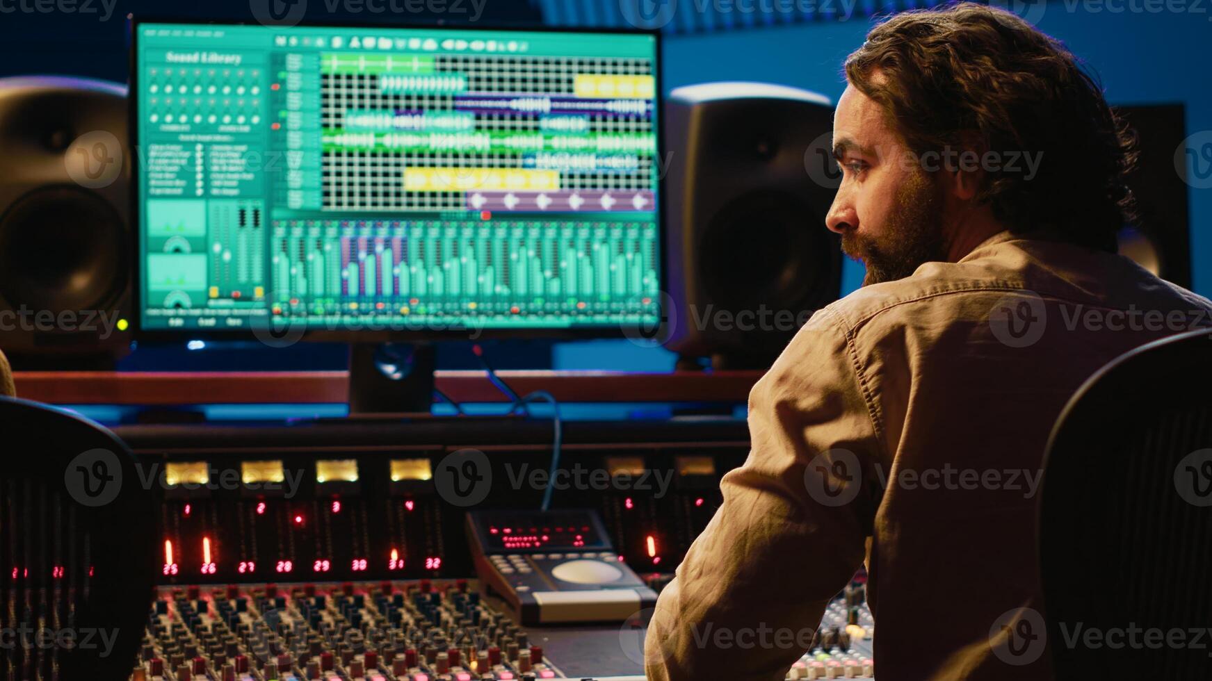 Team of artist and technician editing audio after recording session in control room, mixing and mastering tracks on console in control room. Pressing buttons and pushing sliders. Camera A. photo