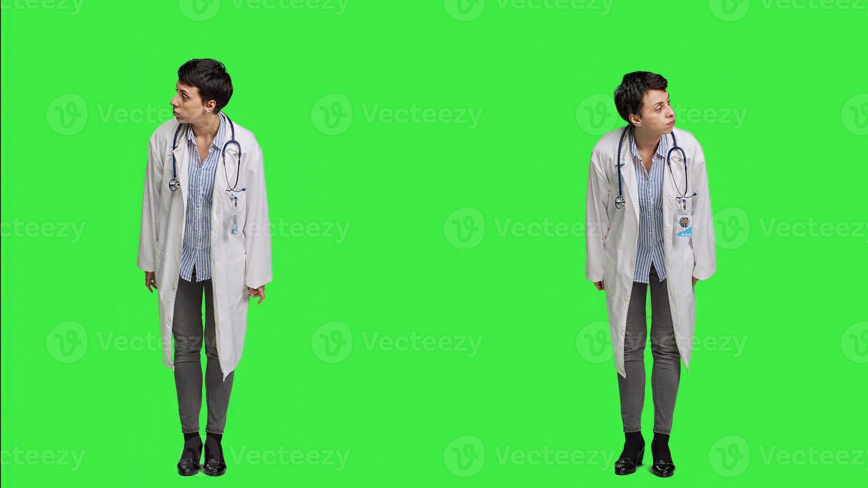 Woman physician looking around for patients to come at checkup exams, waiting for someone standing against greenscreen backdrop. General practitioner with white coat feeling impatient. Camera A. photo