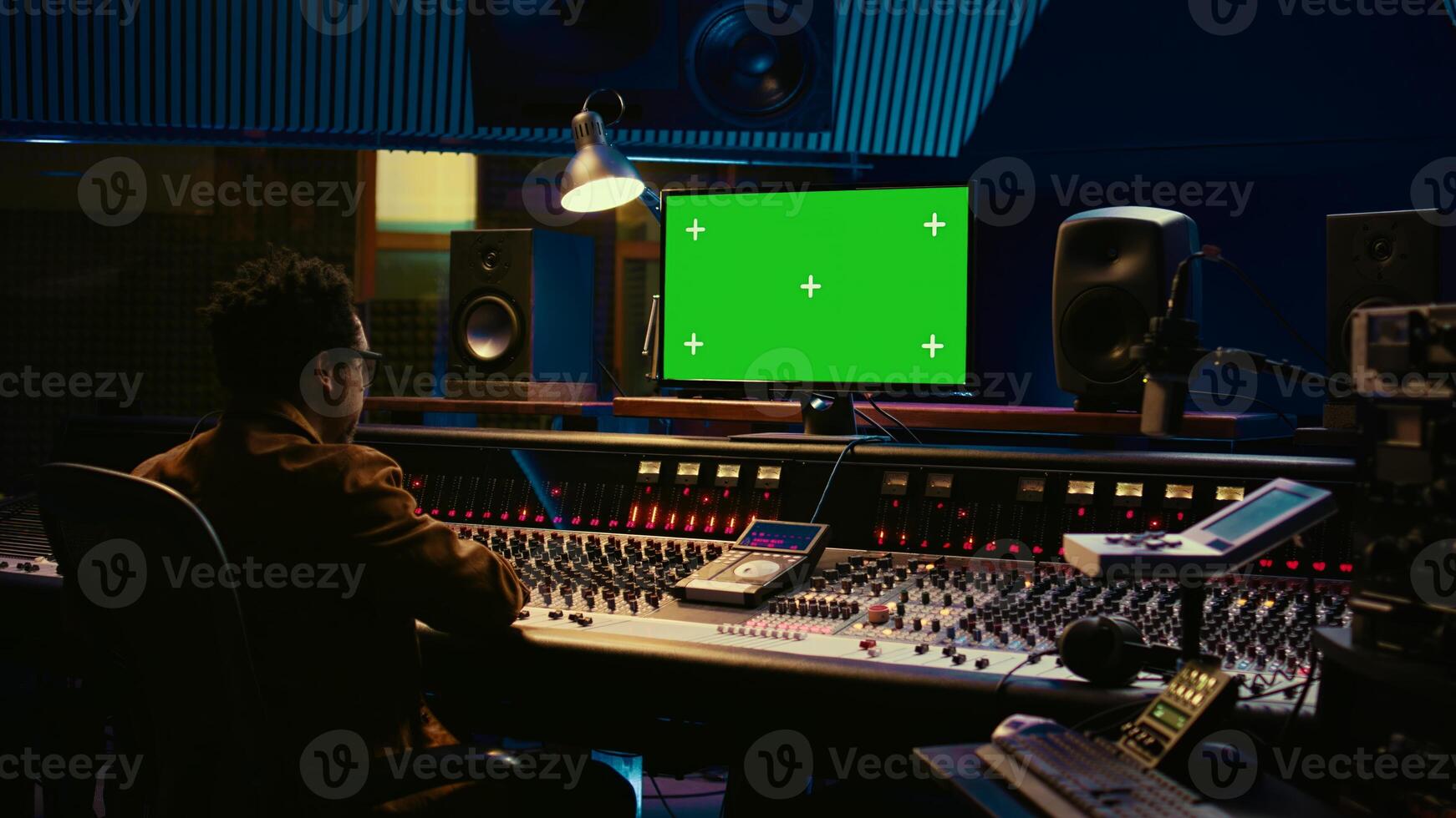 African american sound engineer working in control room with mixing console, tracking music and editing by adjusting volume levels. Skilled technician adjusting volume levels with buttons. Camera B. photo