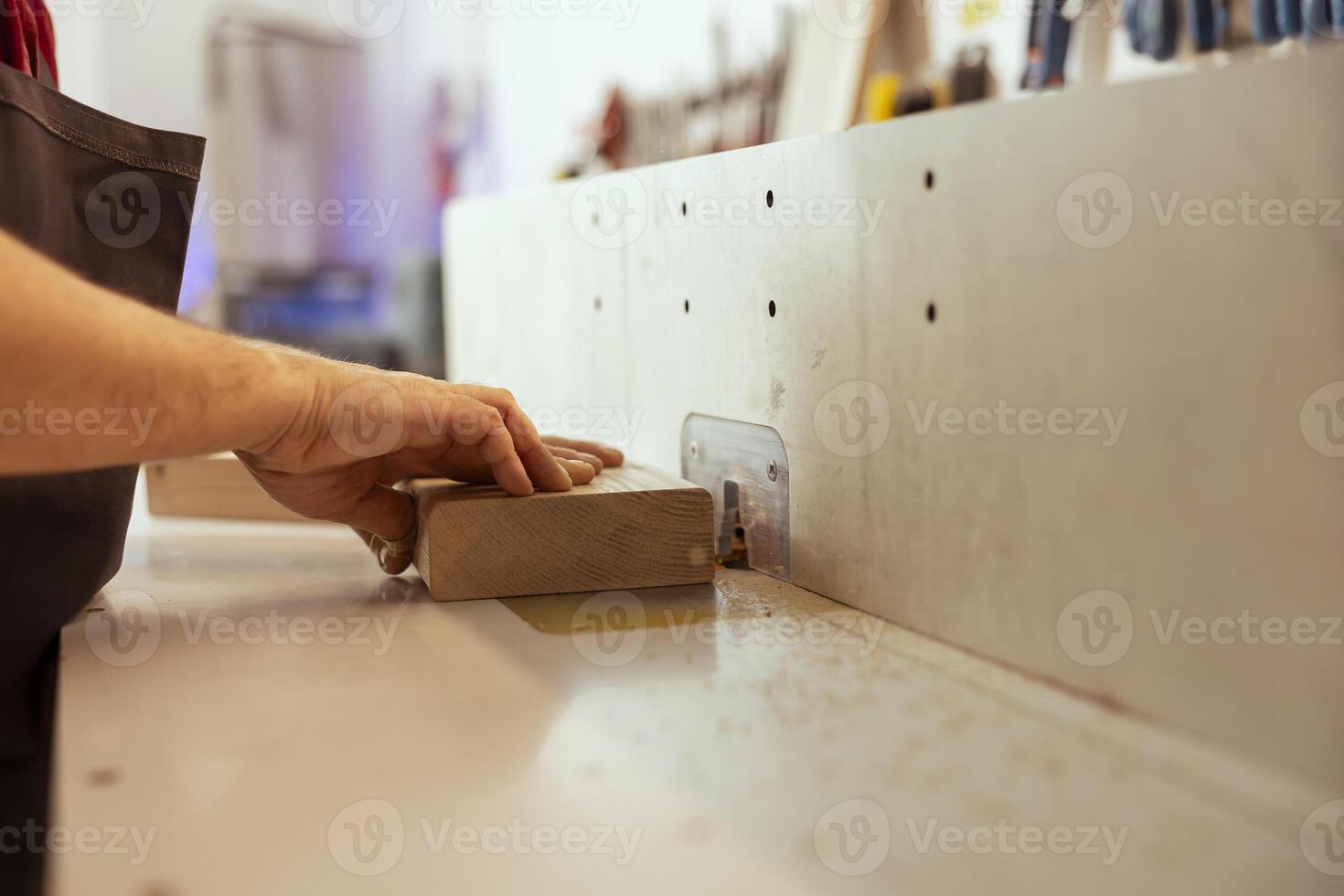 Artisan using wood shaper machinery to finish customer commissioned work on wooden art piece in studio. Woodworking artist in assembling shop using spindle moulder equipment to do crafting photo