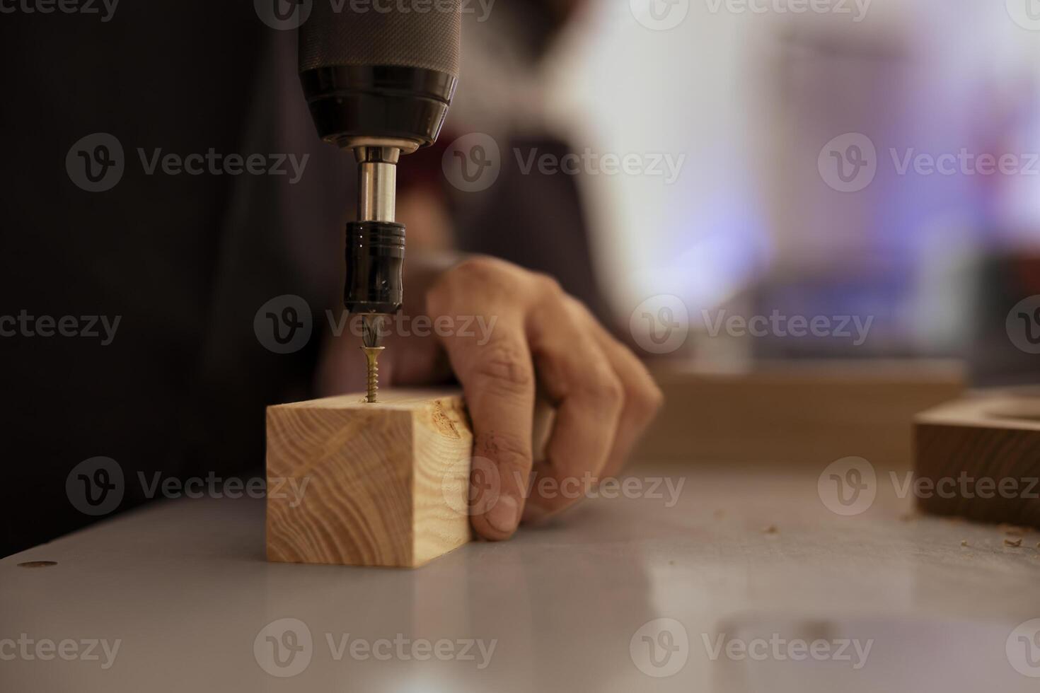 Woodworker in assembly shop using power drill to create holes for dowels in wooden board. Carpenter sinking screws into wooden surfaces with electric tool, doing precise drilling for seamless joinery photo