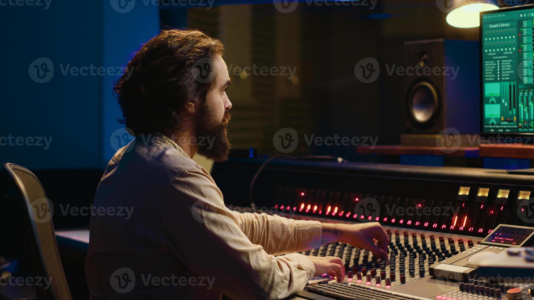 Control room sound engineer editing music with sliders and knobs, working on post production in professional soundproof studio. Technician producing songs on stereo mixing console. Camera A. photo