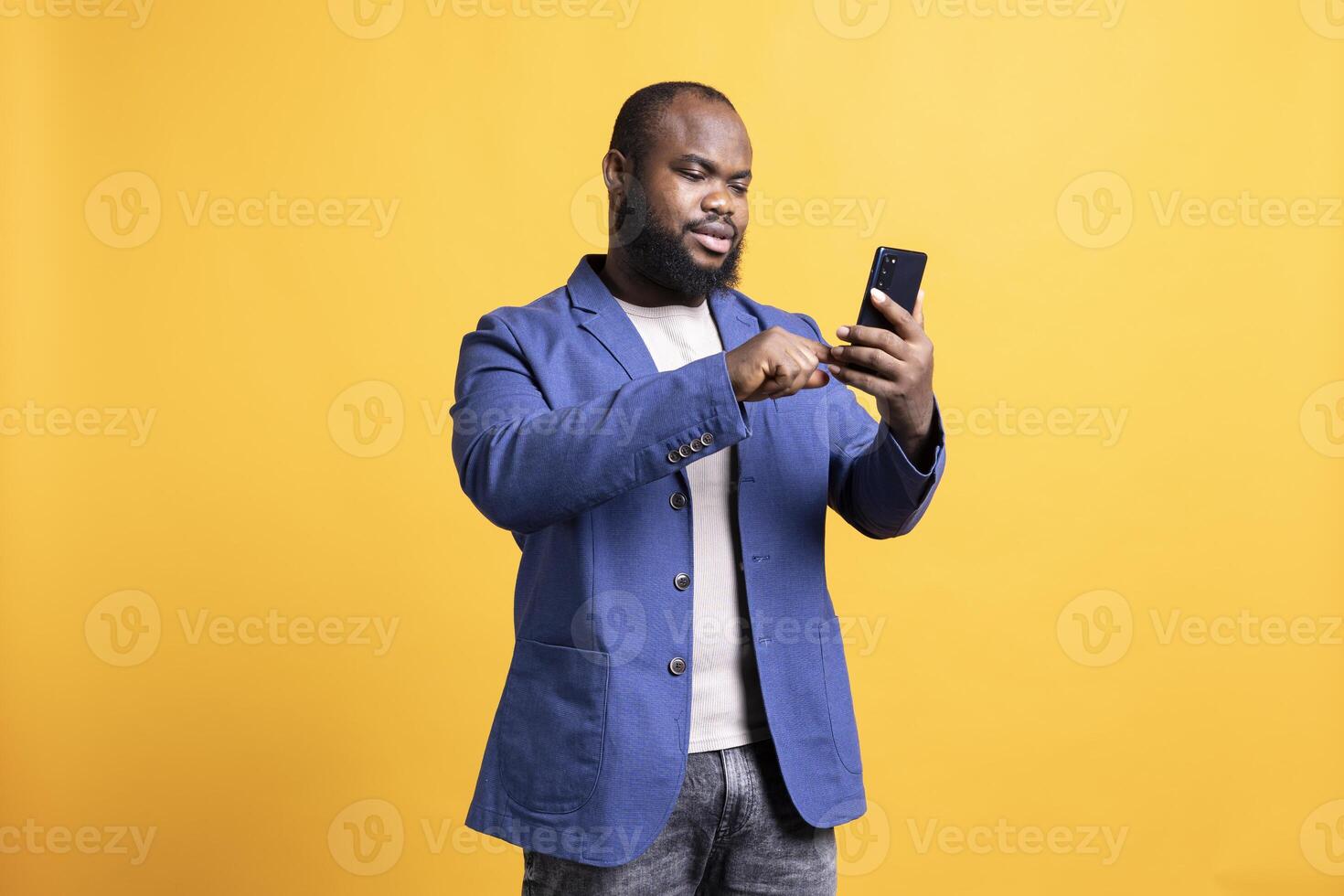 Man scrolling on smartphone touchscreen, using mobile phone to check social media feed. African american person browsing internet websites, isolated over studio background photo