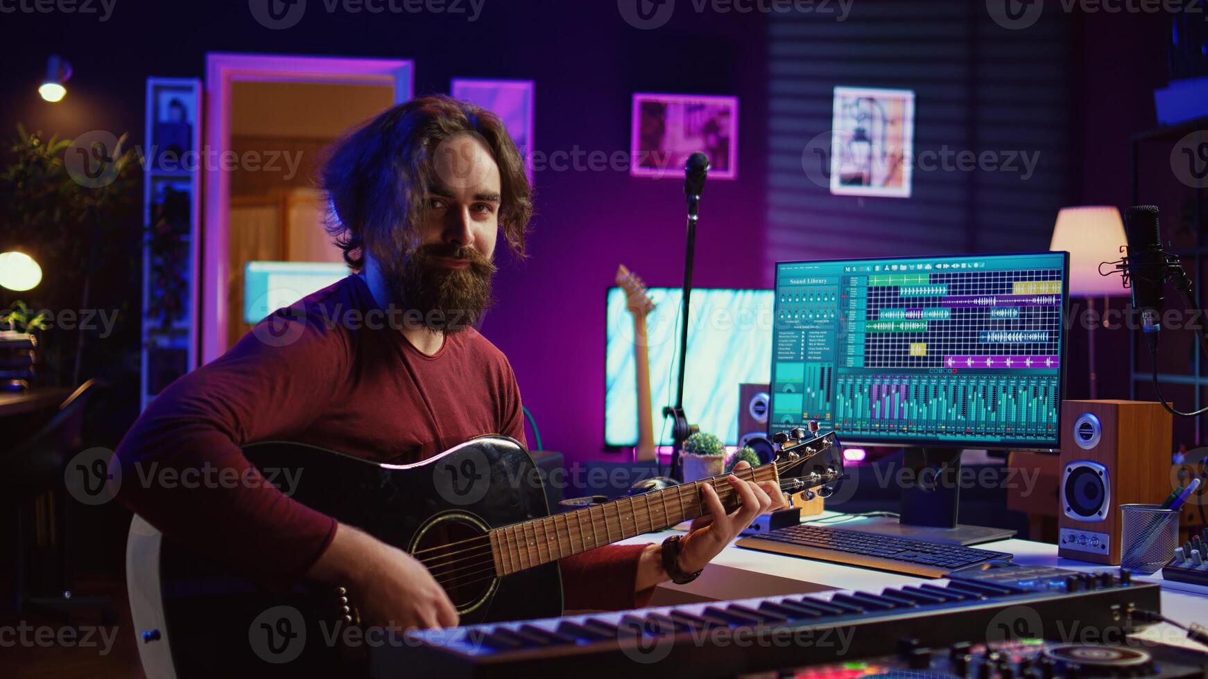 Musician plays acoustic guitar and records melody to compose new song and tunes. Computer screen showing DAW software interface with soundtracks, sound engineer in music production. Camera B. photo