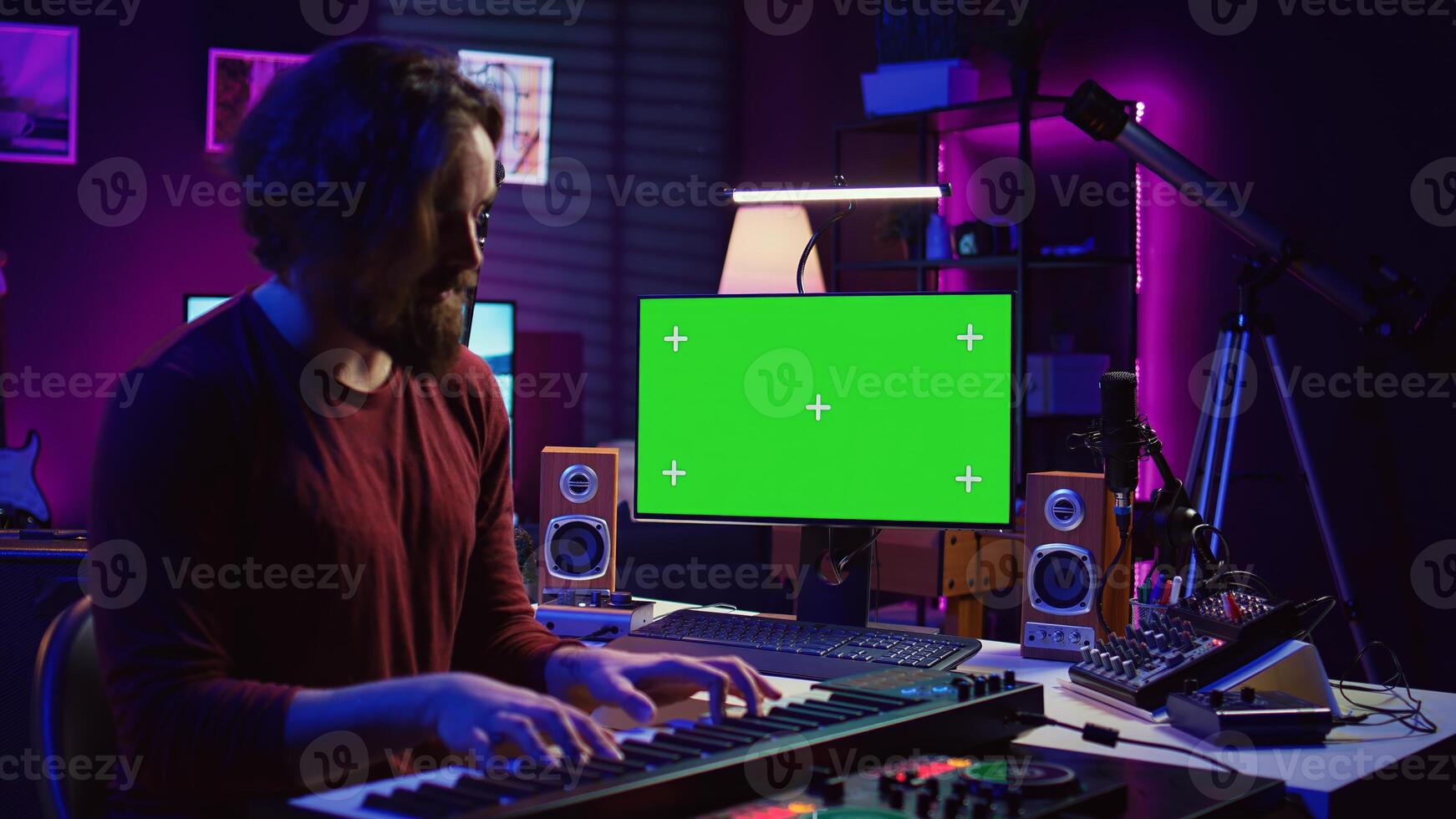 Artist learning to play at electronic piano keyboard in home studio, watching tutorial online with greenscreen display. Music producer practices playing on midi controller synthesizer. Camera B. photo
