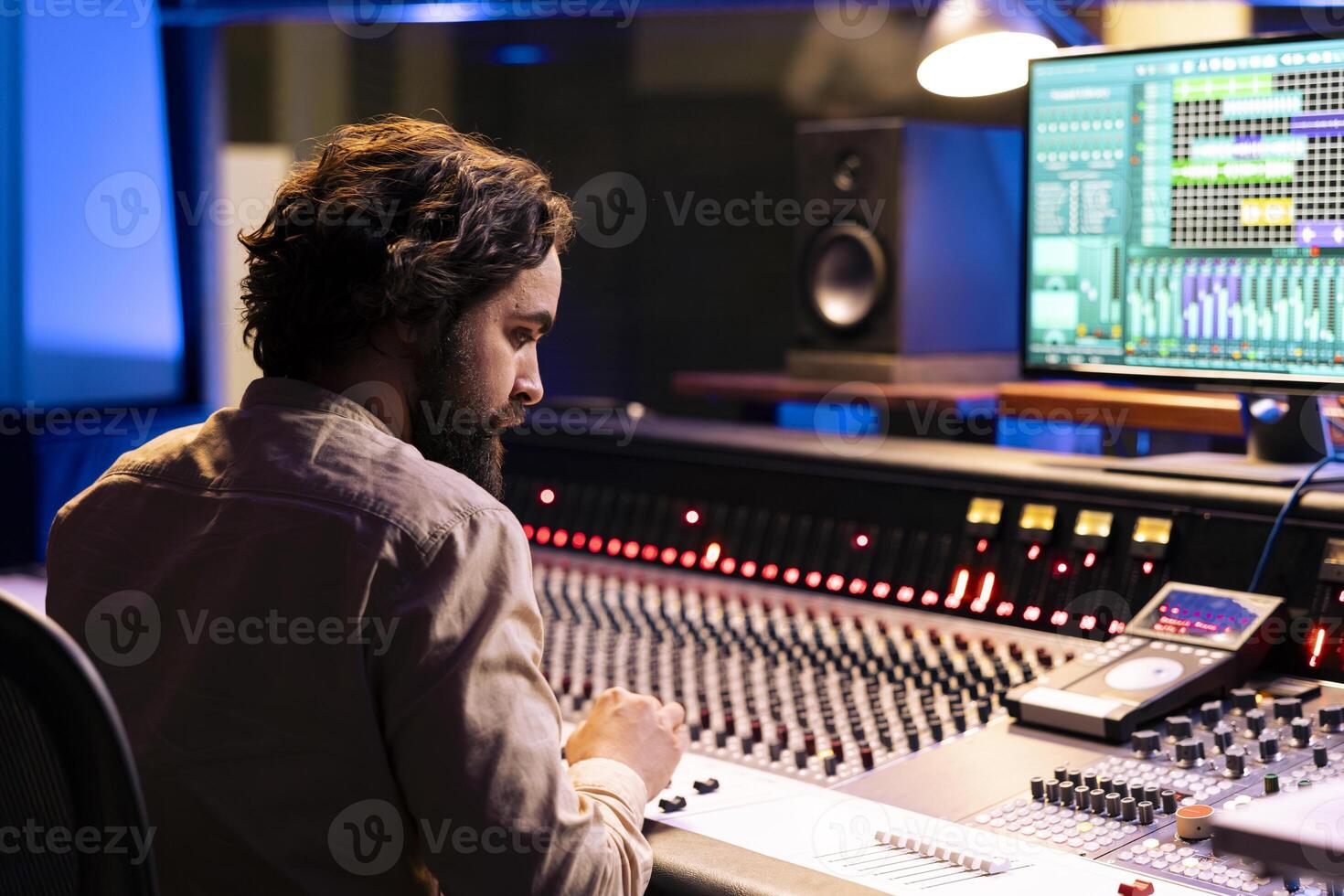 Music producer working on mixing and mastering music with daw software, editing tracks with audio console dashboard. Young sound designer creating sounds and tunes in professional studio. photo