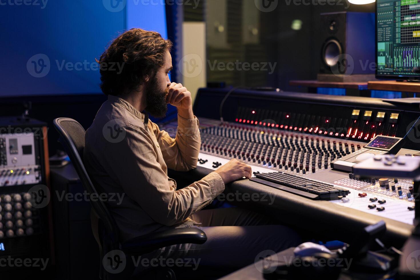 Sound designer mixing and mastering music in recording studio, examines audio digital software on pc before adding effects in post production. Technician works in control room. Close up. photo