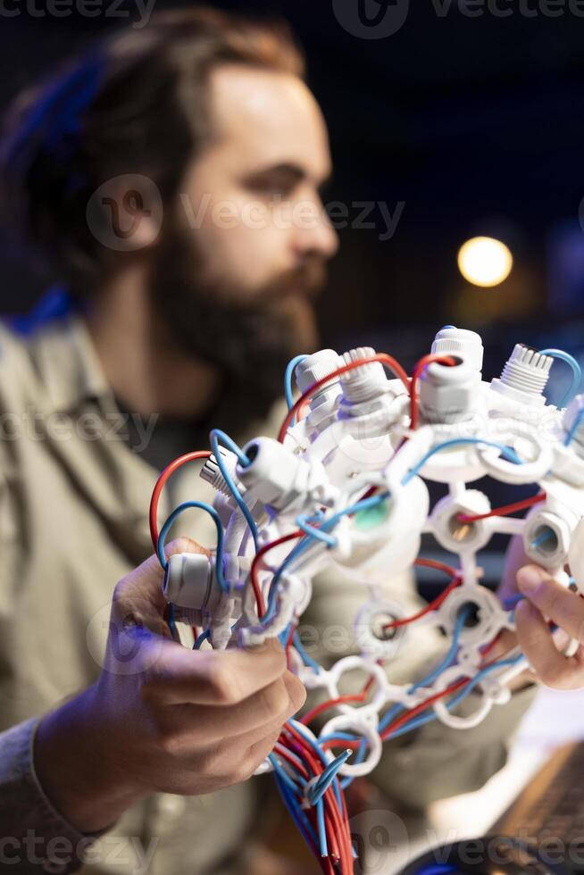 Focus on EEG headset used by IT professional in blurry background to communicate with artificial intelligence on computer. Close up shot of high tech device used by software developer photo