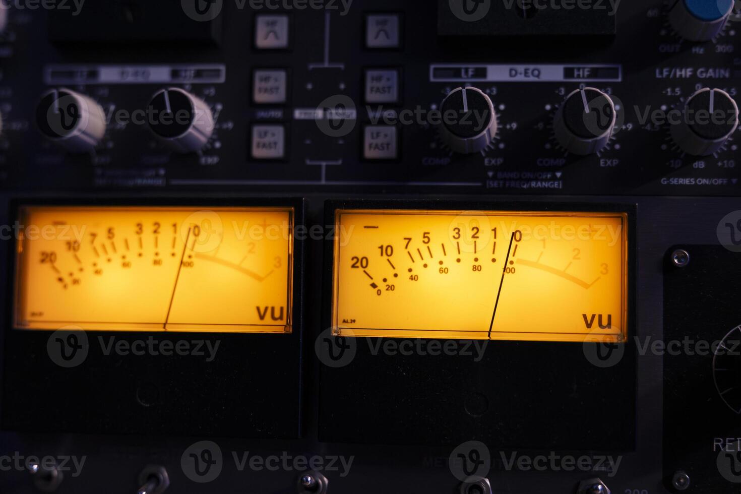 Technical recording equipment and devices for calibrating volume levels and sound settings in professional studio control room, yellow light. Audio mixer desk with switchers and sliders. Close up. photo