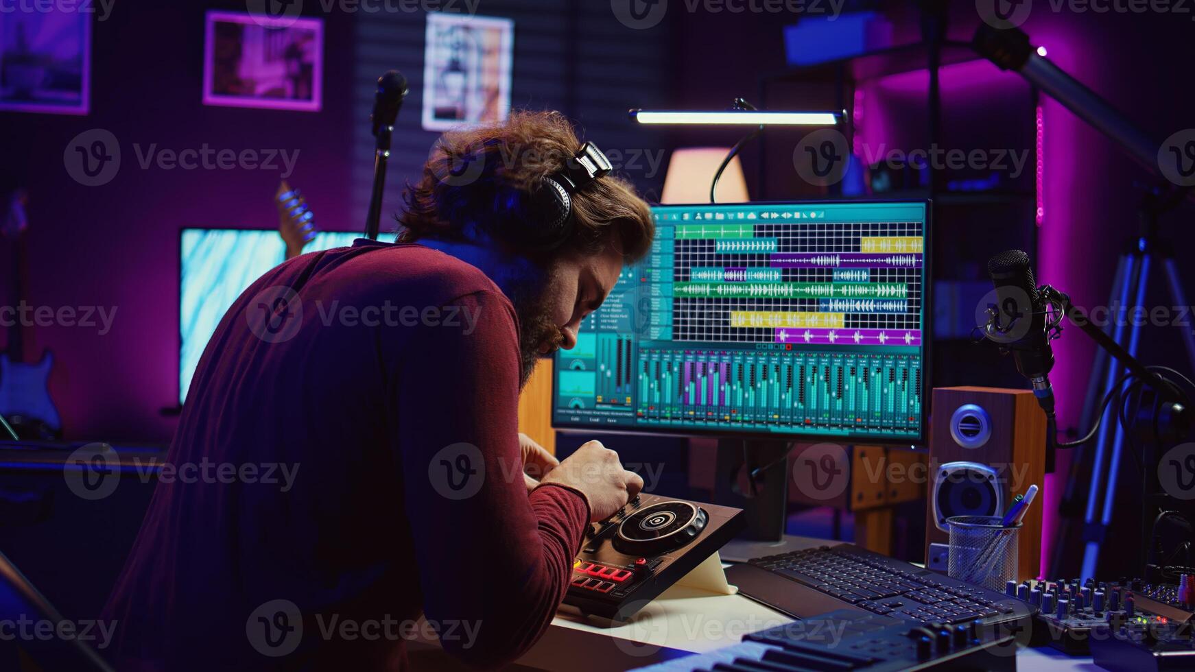 Audio technician mixing and mastering songs on daw software, creating fun atmosphere with acoustics and amplifier. Sound designer recording tunes on dj panel board in his home studio. Camera B. photo