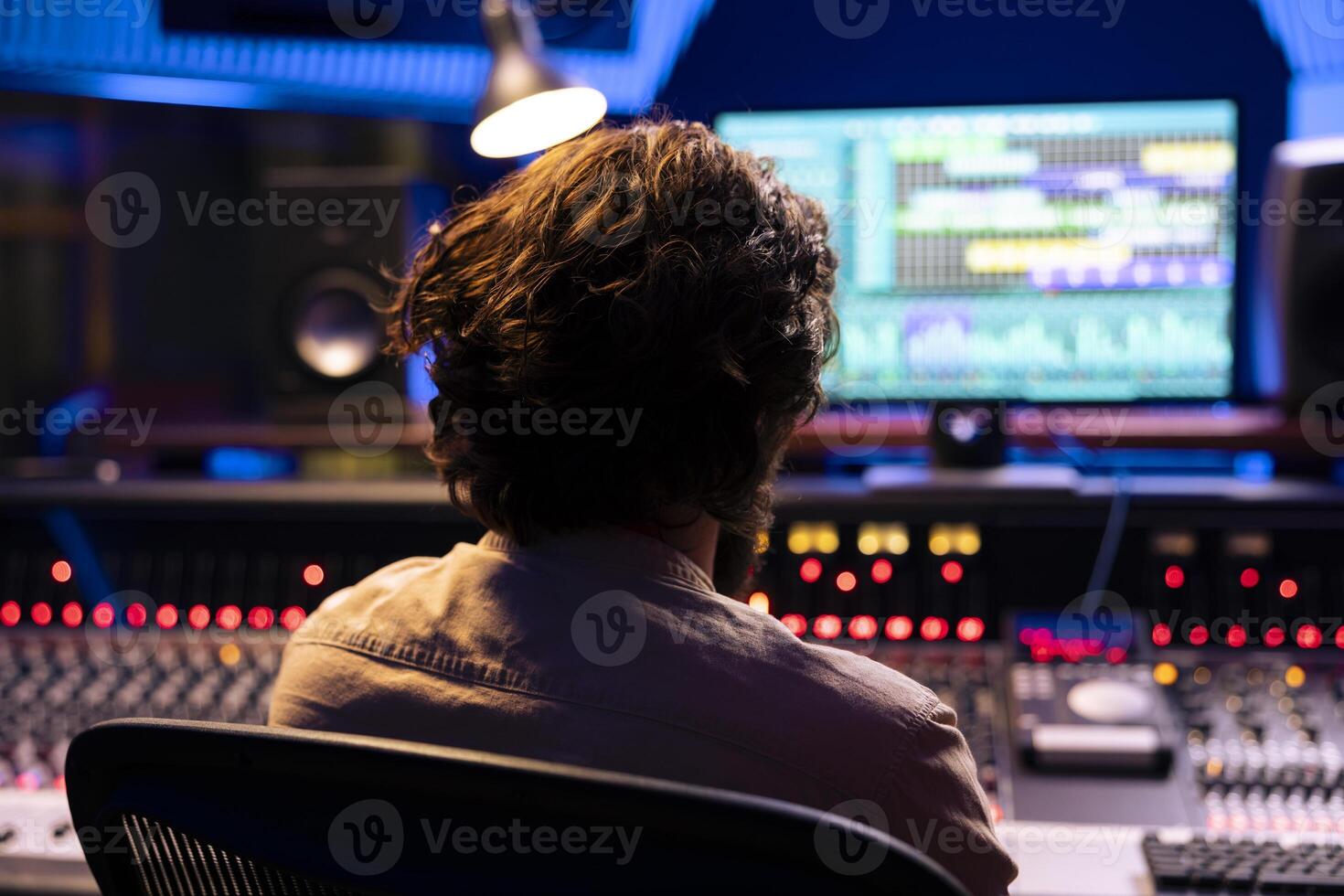 Sound designer tuning audio recordings with faders and buttons on control desk in professional music studio, mixing and mastering tracks for a new album. Adjusting volume levels with equalizer. photo
