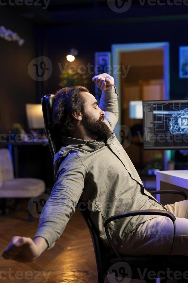 Software technician stretching after using computer all day to build artificial intelligence simulating human brain. Fatigued IT admin relaxing after finishing working with AI neural networks on PC photo