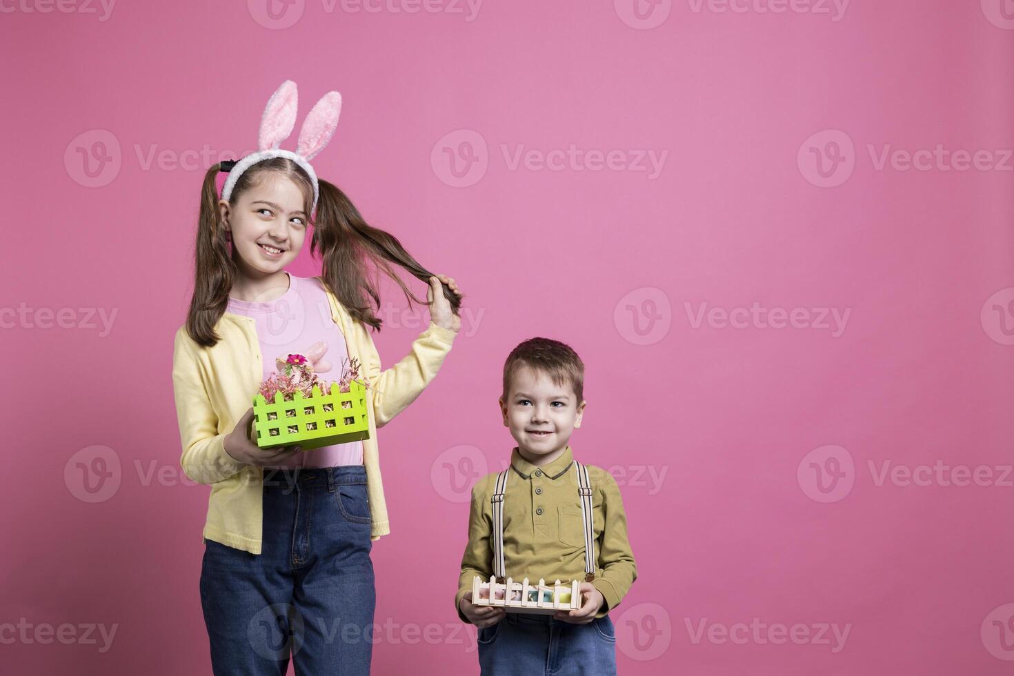 Positive cute children presenting festive handmade ornaments on camera, feeling joyful about easter holiday event and spring time. Brother and sister show their baskets with painted eggs. photo