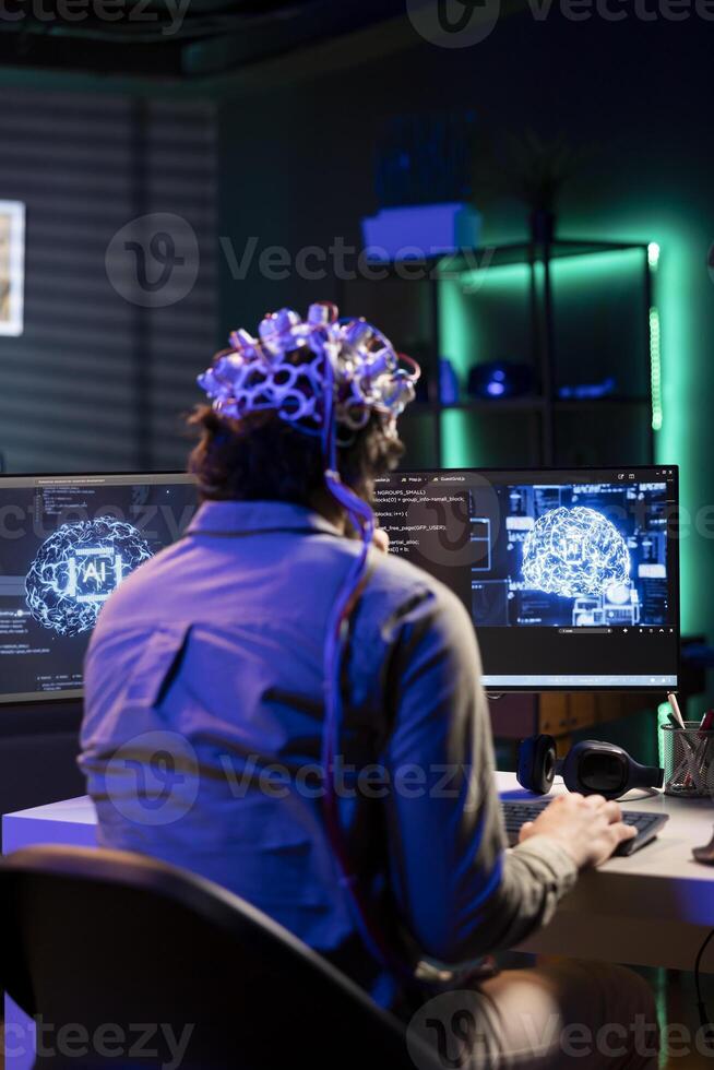 Software technician with EEG headset on programming brain transfer into computer virtual world, merging with artificial intelligence. IT expert using neuroscience to gain digital soul photo