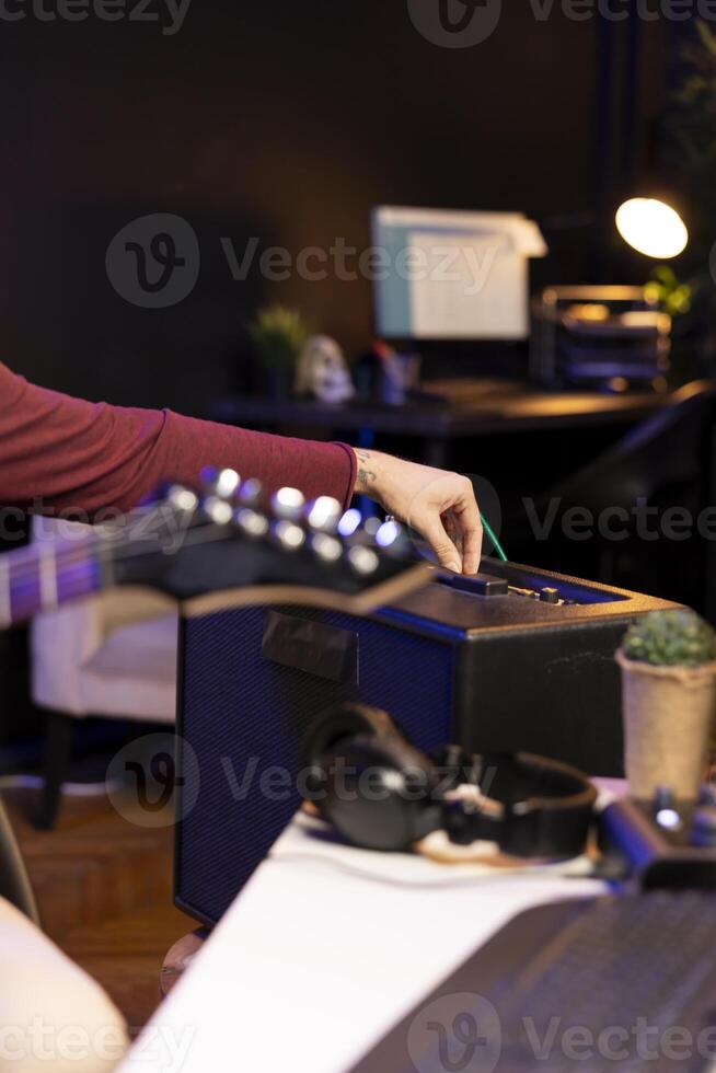 sonido productor ajustando volumen niveles en hogar estudio amplificador antes de grabación guitarra melodías para mezcla y dominar sesión. masculino compositor creando un nuevo canción con estéreo engranaje. cerca arriba. foto