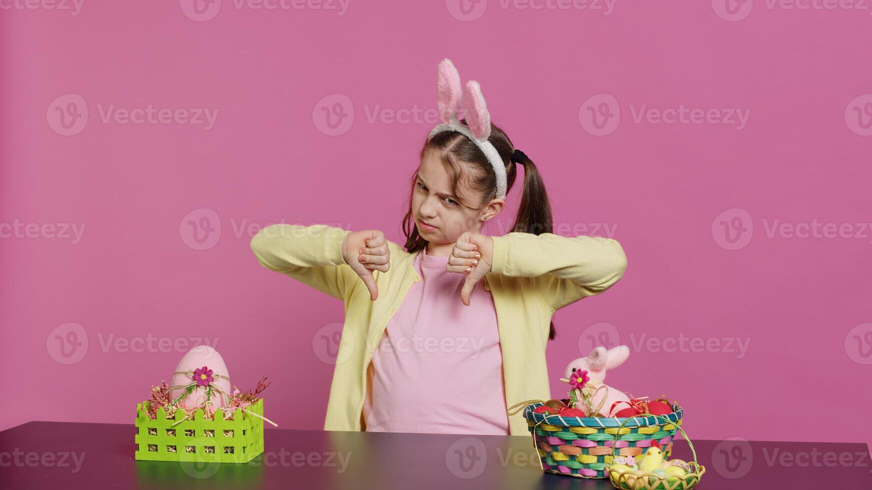 Displeased unhappy child giving thumbs down in studio, expressing her disapproval and disagreement with dislike symbol. Angry dissatisfied young girl showing negative bad gesture. Camera A. photo