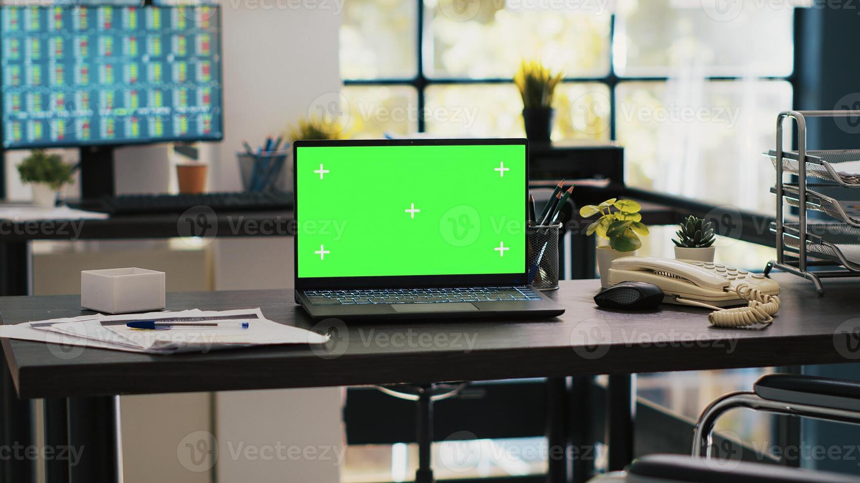 Wheelchair in office offering accessibility to workers with disability and green screen laptop on desk. Mockup notebook in workspace and computer screen in background displaying stock exchange photo