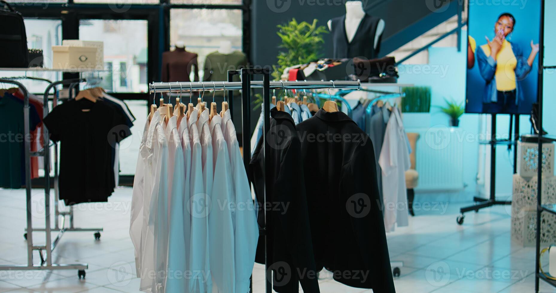 Empty trendy clothing store selling fashionable items and shoes, filled with new casual or formal merchandise. Shopping center boutique having fashion collection on racks, bags on display. Camera B. photo