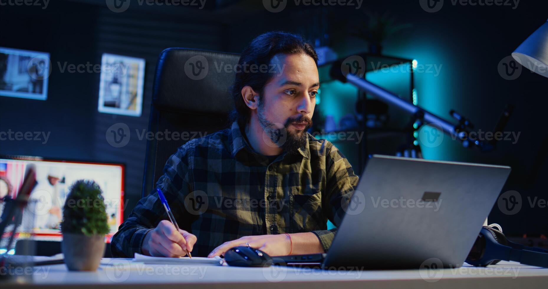 Man at home paying attention in elearning seminar on laptop to online class teacher, writing down information. Homeschooling student listening to internet course lesson and doing homework photo