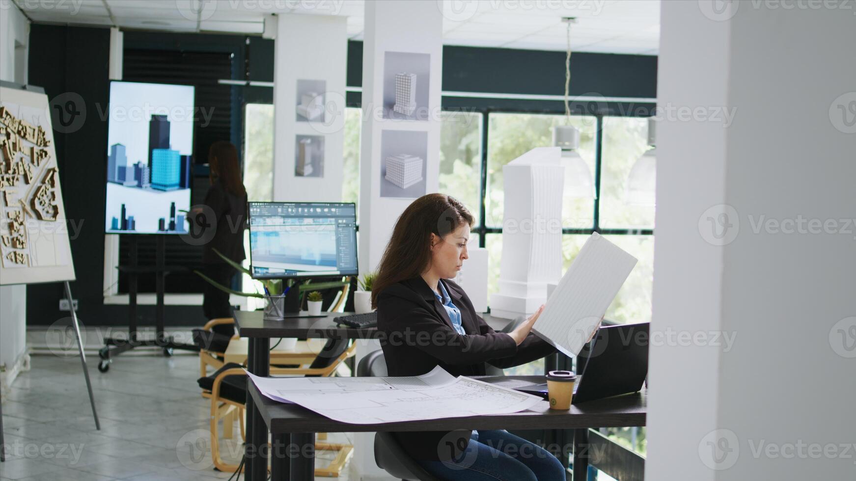 arquitectónico técnico examina 3d edificio modelo en creativo agencia trabajo colaborativo espacio, tomando notas de diseño líneas y mediciones. mujer medición maqueta escala y elementos. trípode disparo. foto