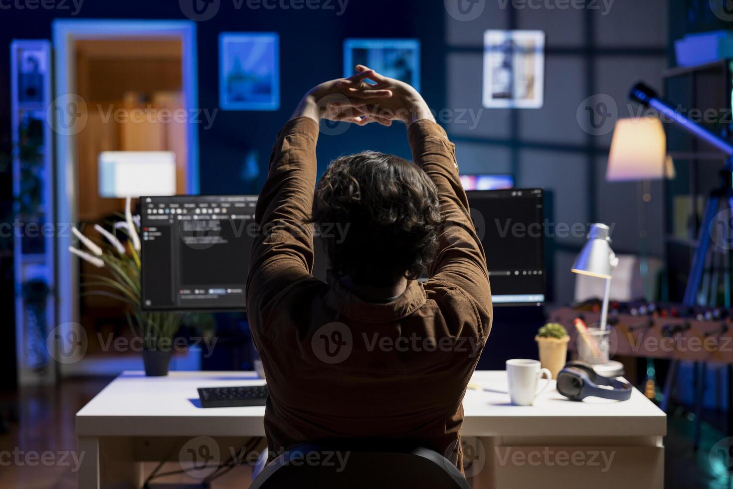 Programmer stretching body limbs after securing company servers from virus attacks all day. Fatigued IT remote employee relaxing tense muscles at desk after building firewalls protecting data photo