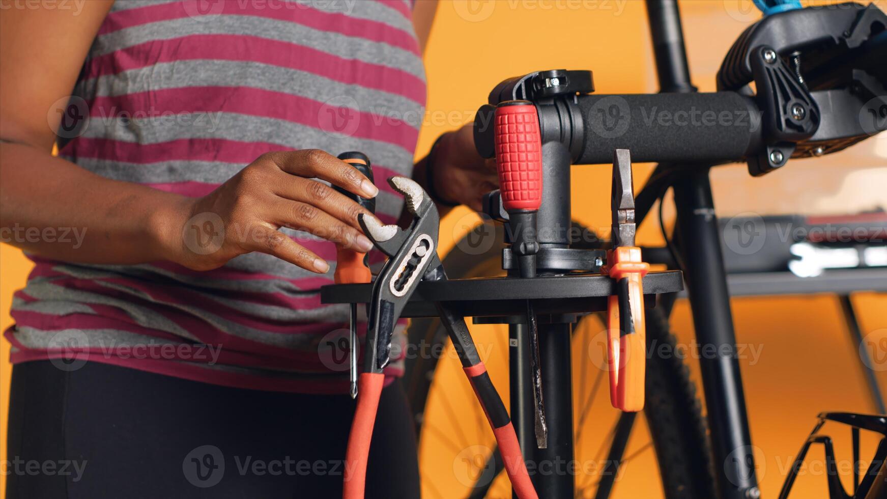 Close up of specialist preparing work tools before starting patching up faulty bicycle parts. Employee arranging screwdriver, pliers and hex wrench on equipment support, handheld camera shot photo