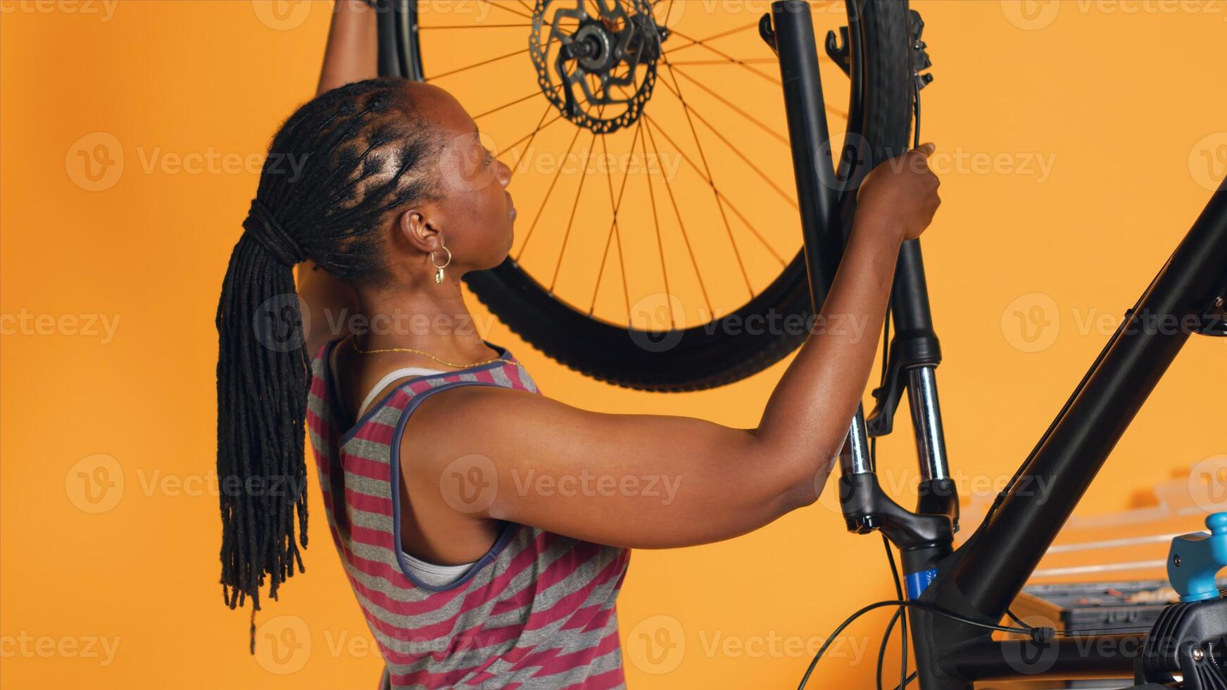 Woman doing bike servicing in studio background atelier shop, searching substitute for defective wheel. Technician fixing faulty bicycle tires and servicing damaged rear derailleur photo