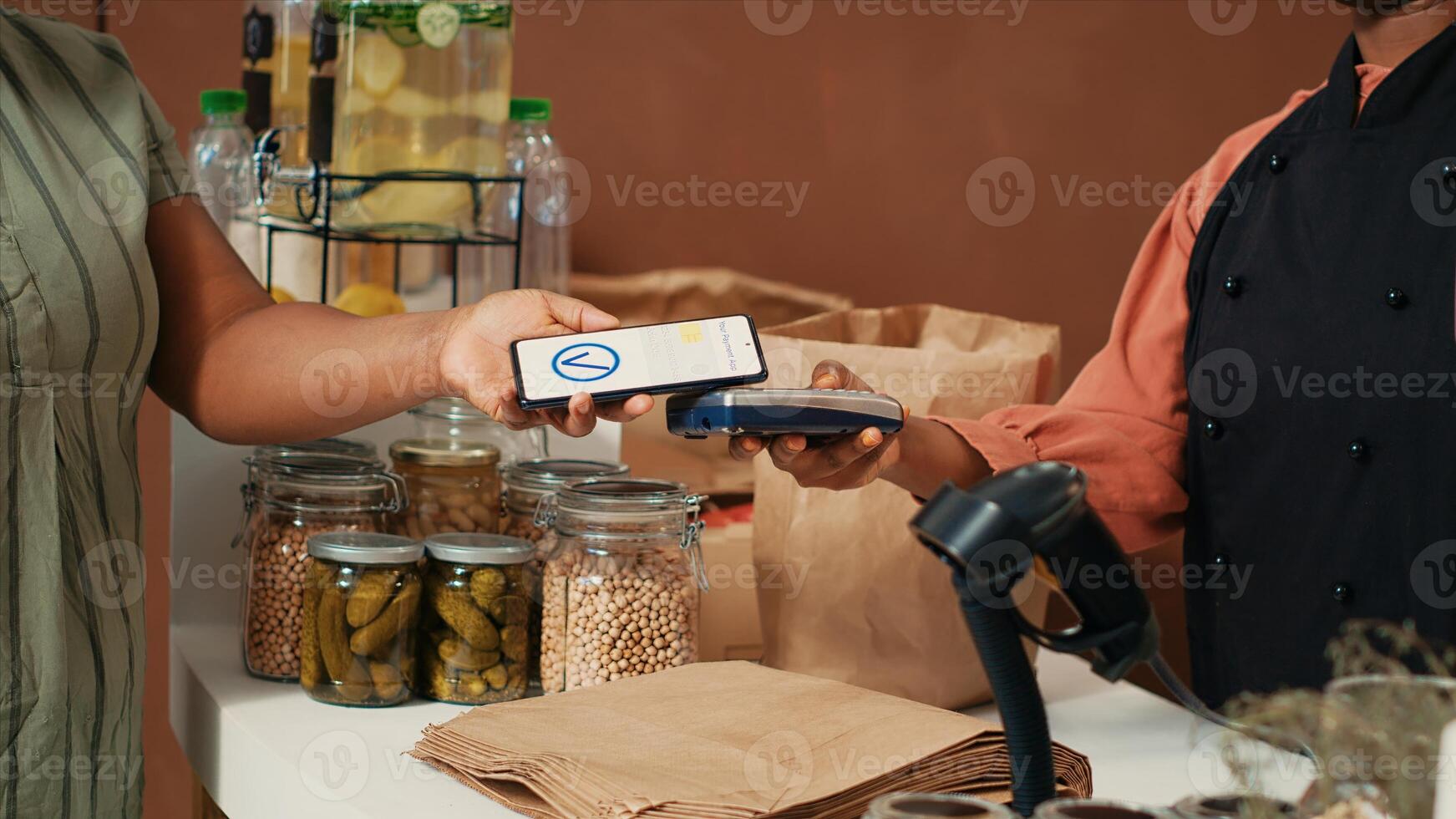 africano americano mujer comprando Fresco bio Produce con nfc móvil pago a posición, secundario sostenible estilo de vida y sano comiendo. comprador mirando para orgánico de cosecha propia frutas y vegetales. foto