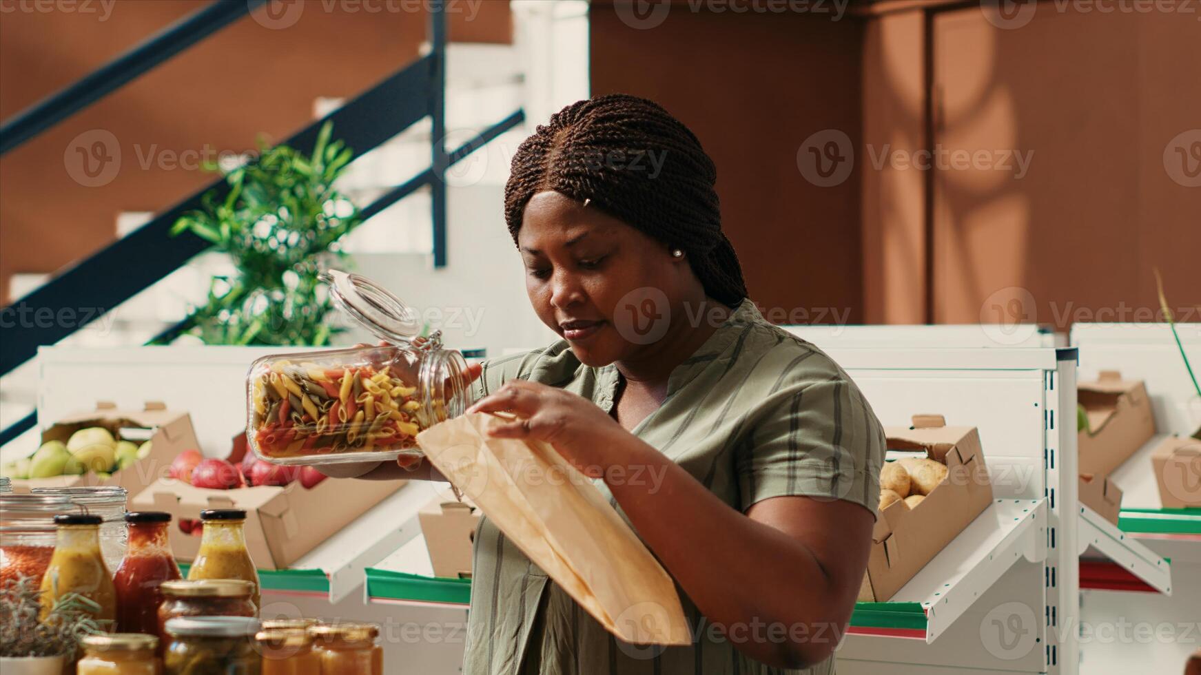 Customer pouring a type of pasta in ecological paper bag used to buy bulk products at zero waste store. Vegan woman searching for organic bio food alternatives at natural farming shop. photo