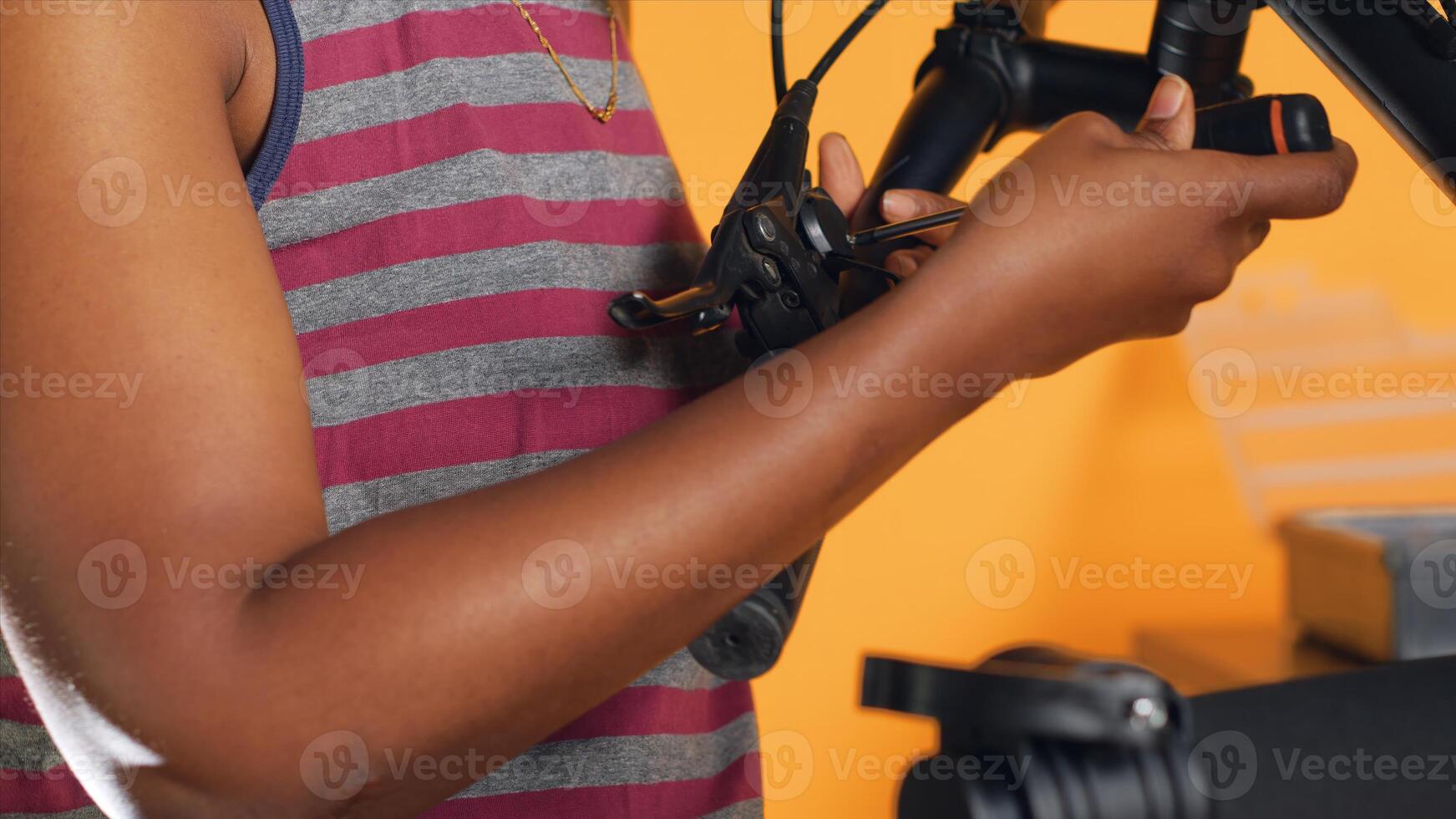 Handyman uses screwdriver to tighten brake levers screws on bicycle handlebars, studio background . Close up shot of repairman unscrewing damaged bike parts in order to refurbish them photo
