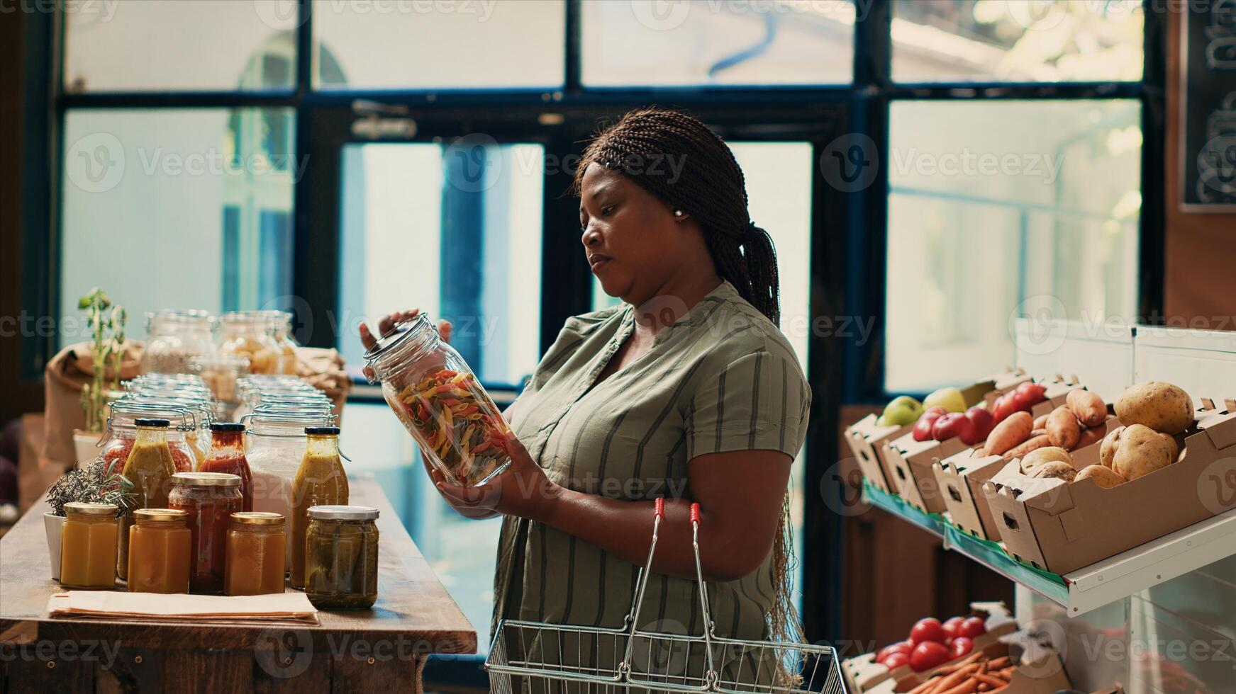 Client looks for organic natural food items in zero waste store, looking for chemicals free pasta or grains in glass jars. African american buyer supporting sustainable lifestyle and local farming. photo