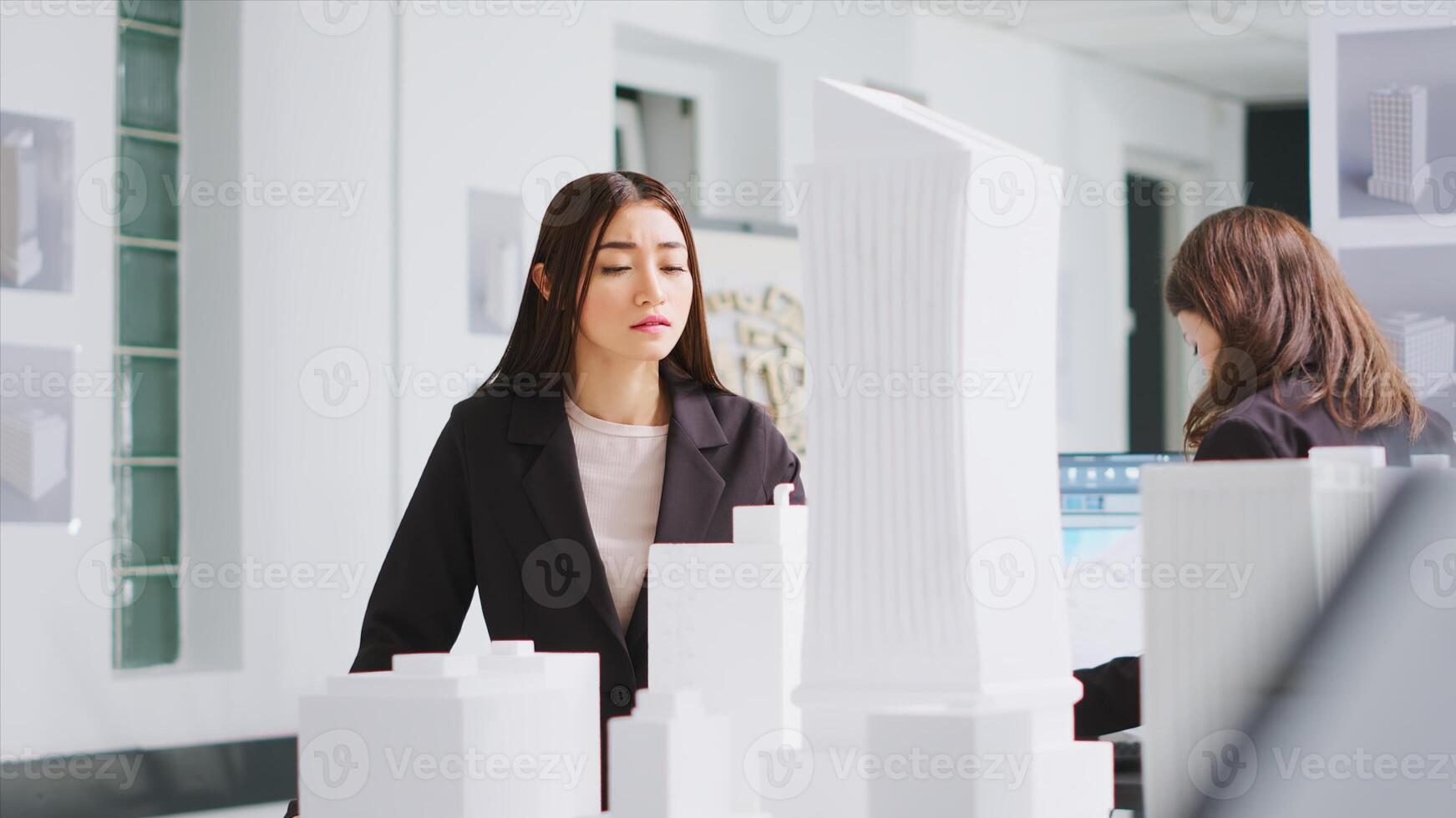 arquitecto analizando planos y 3d edificio modelos a diseño mesa, molesto a desarrollar nuevo industrial plan para residencial zona proyecto. mujer medición el dimensiones y elementos. foto