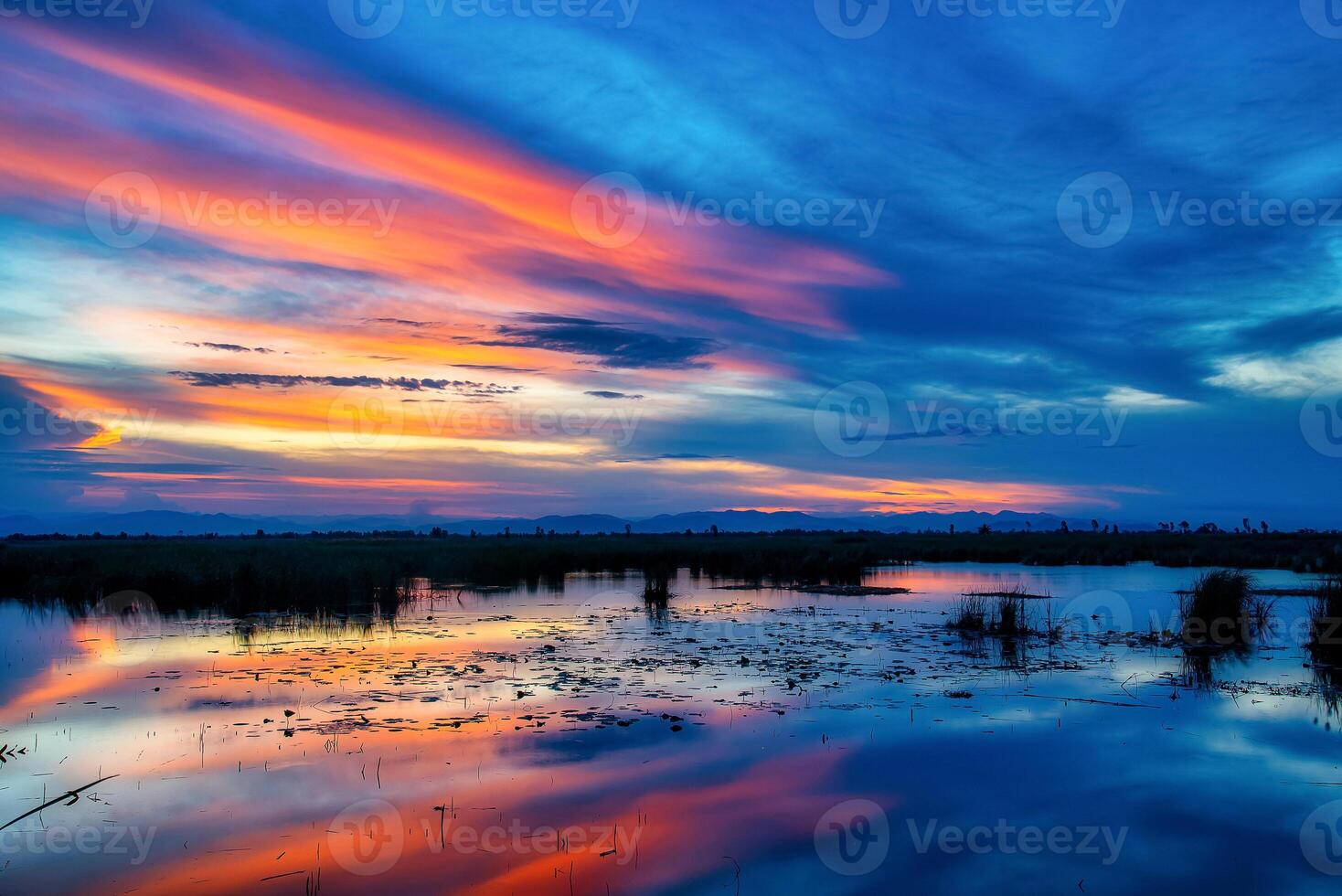 dramático puesta de sol cielo con nubes terminado Mountian y laguna foto