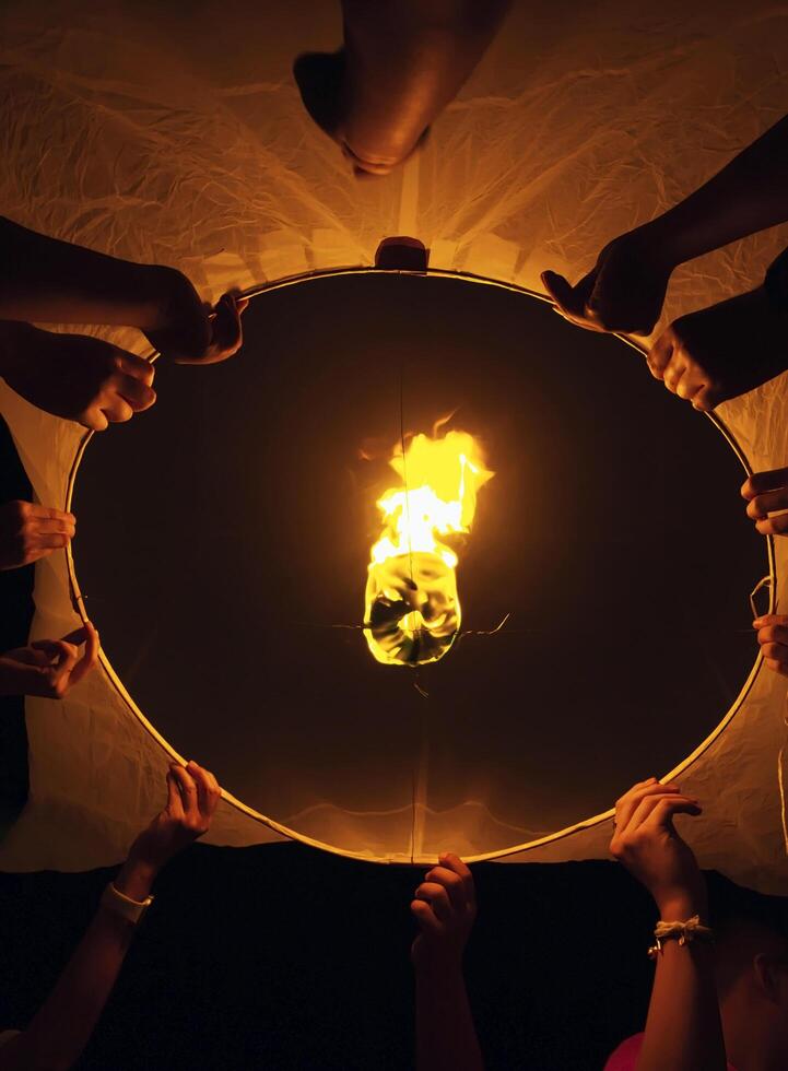 Lanterns are burning and held by many hands at the Yi Peng Lantern Festival. photo