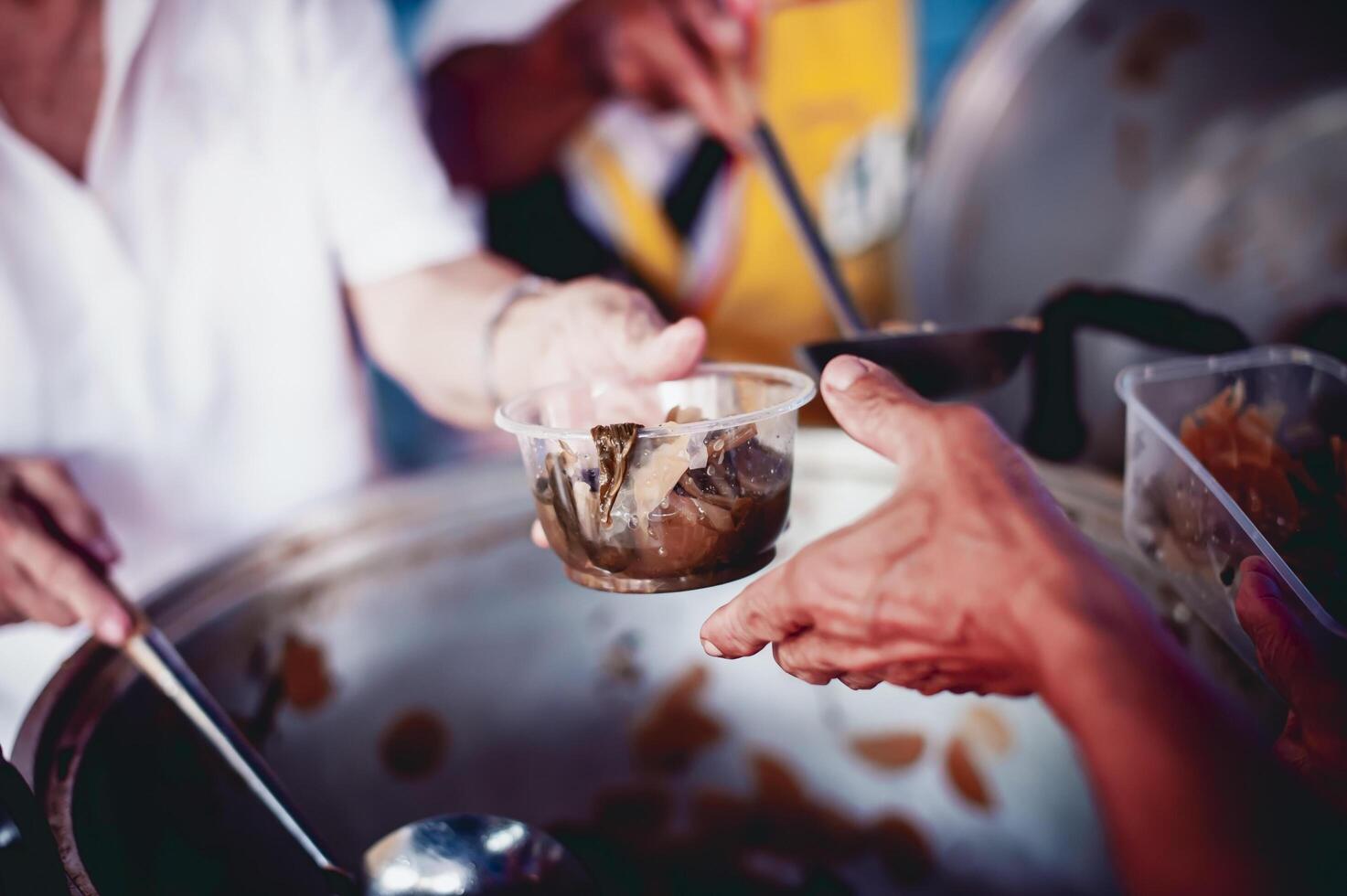 The hands of the poor apply for food from rich people who donate food. photo