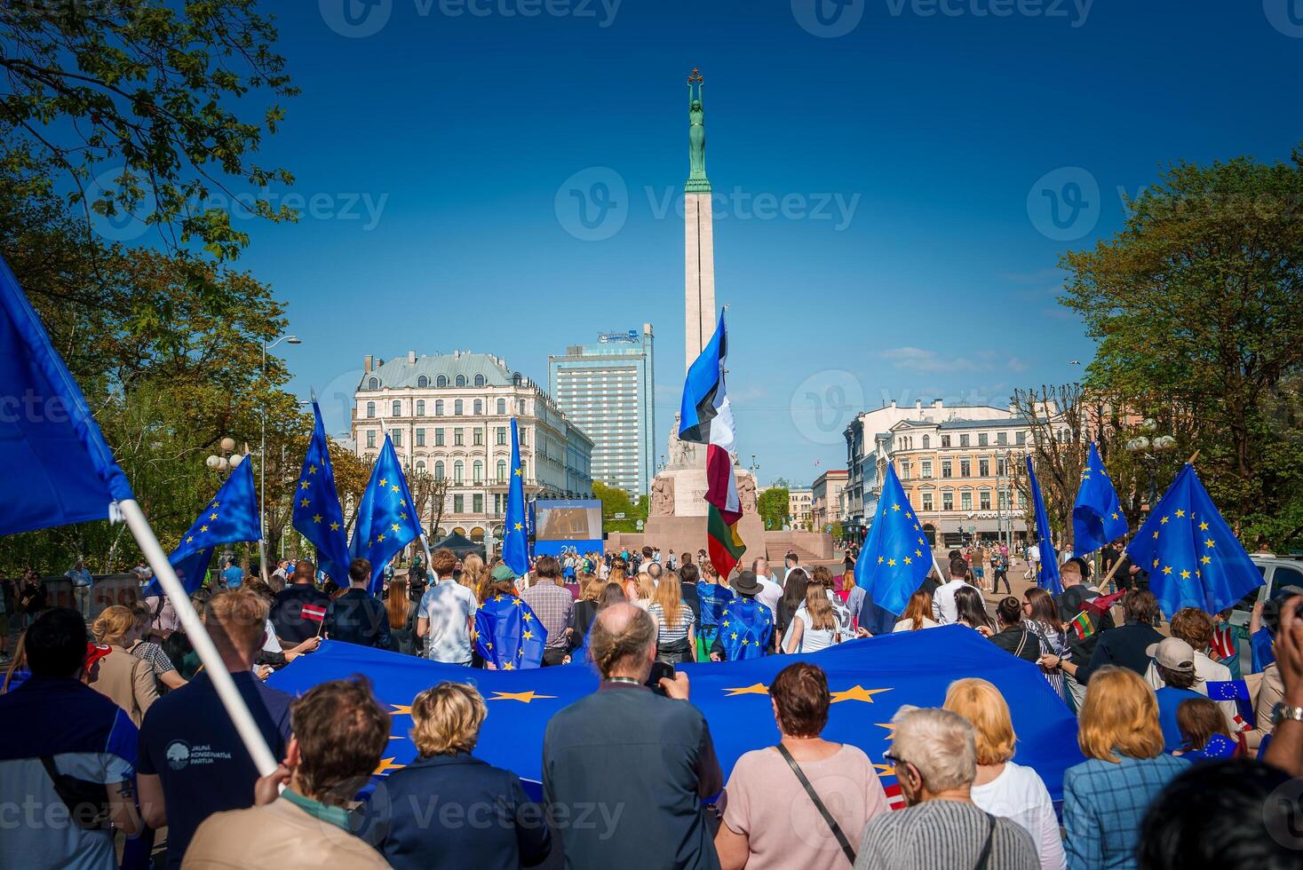 Vibrant celebration in old town of Riga, Latvia, with flags and iconic Freedom Monument photo