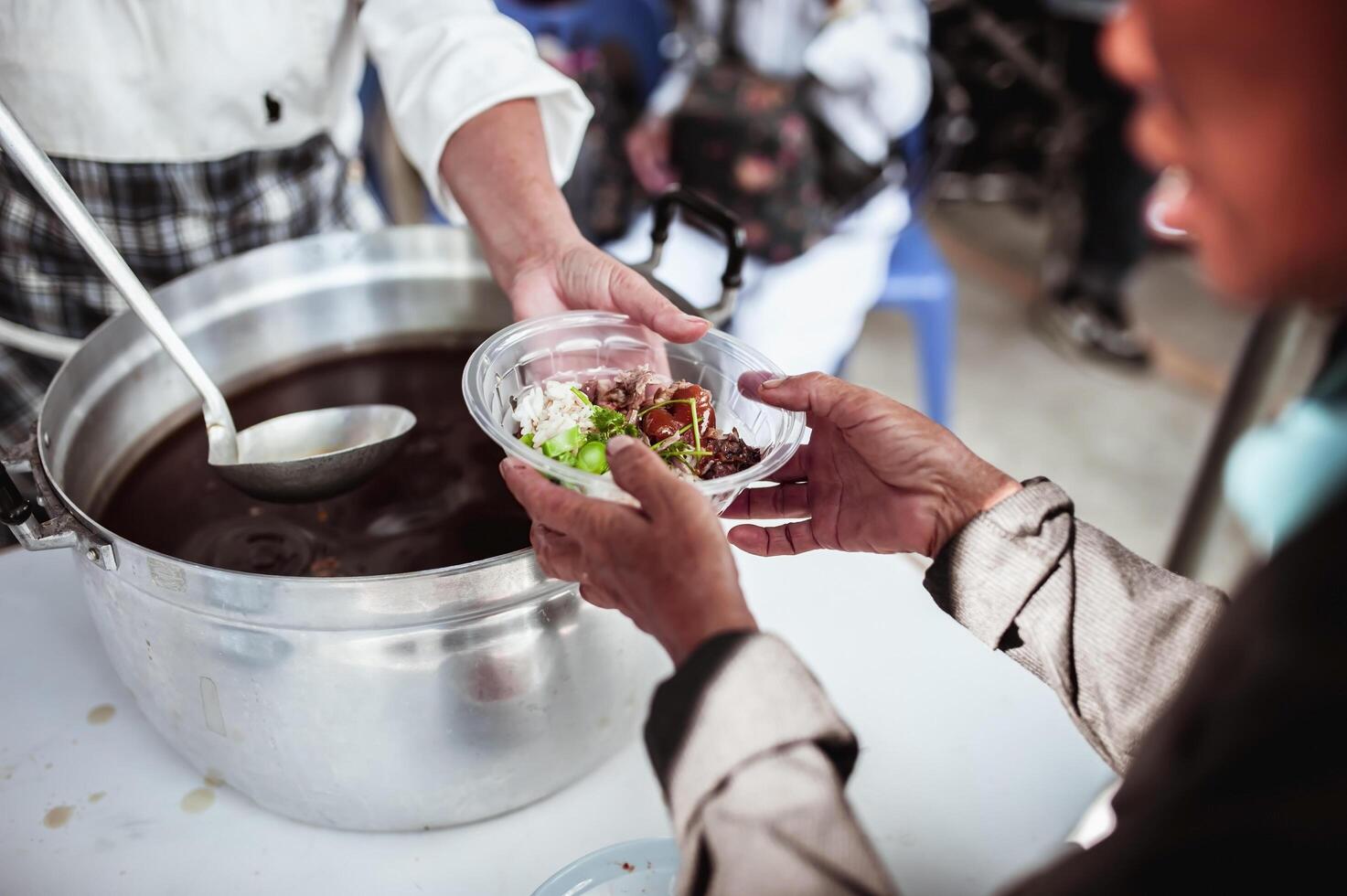 Feeding Concepts . Hand offered to donate food from a rich man Share. The concept of social sharing . Poor people receiving food from donations photo