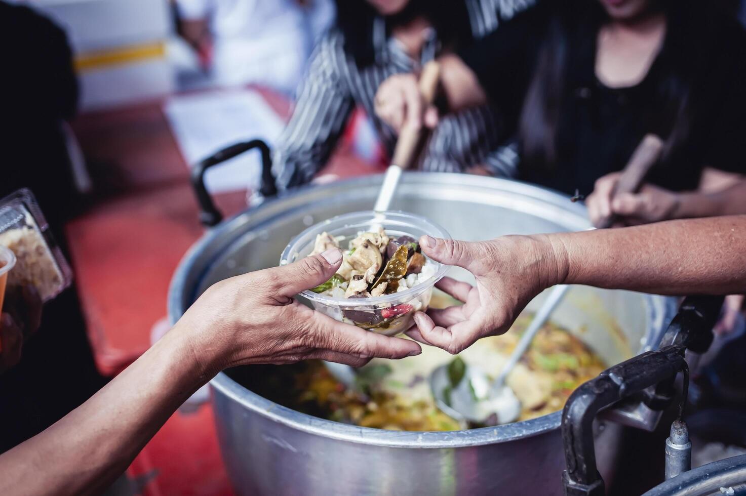 Feeding Concepts . Hand offered to donate food from a rich man Share. The concept of social sharing . Poor people receiving food from donations photo